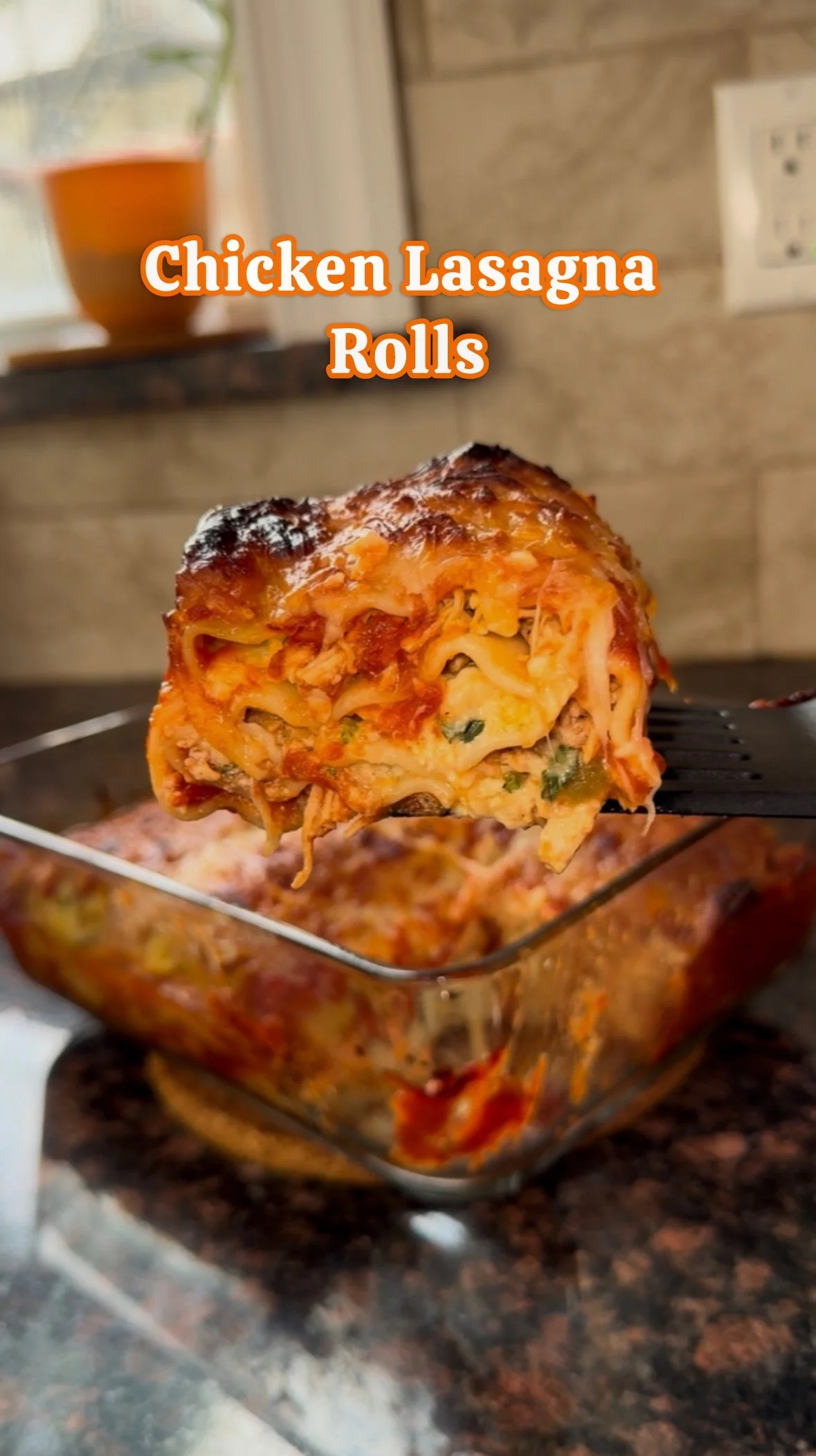 A fork with a slice of chicken lasagna roll held above a glass baking dish filled with chicken lasagna rolls, showing the layered pasta, sauce, and melted cheese.