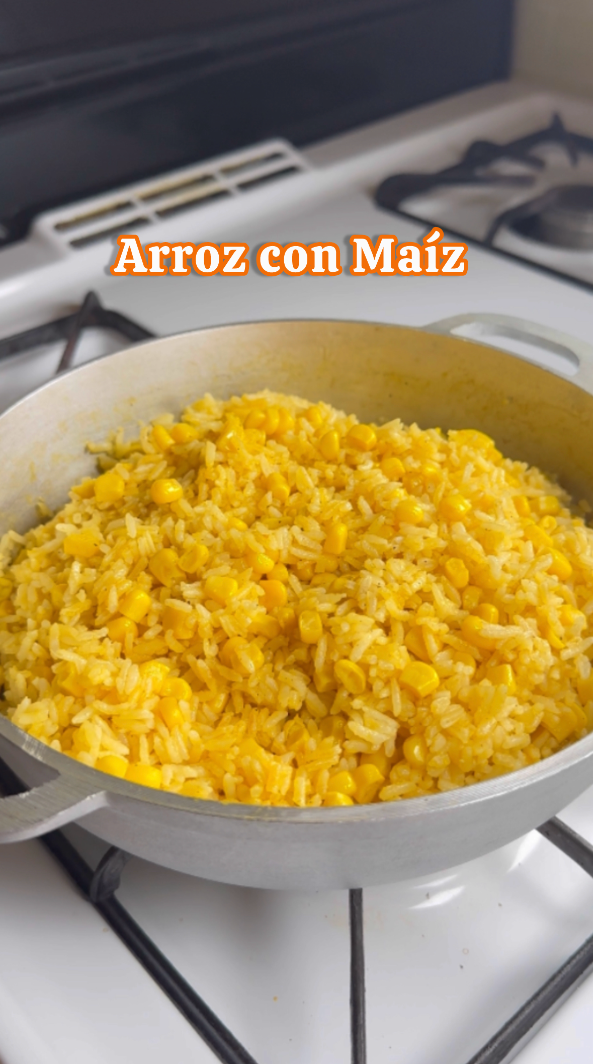 A pot of cooked rice with corn on a stovetop, with Spanish text 'Arroz con Maíz' overlaid.