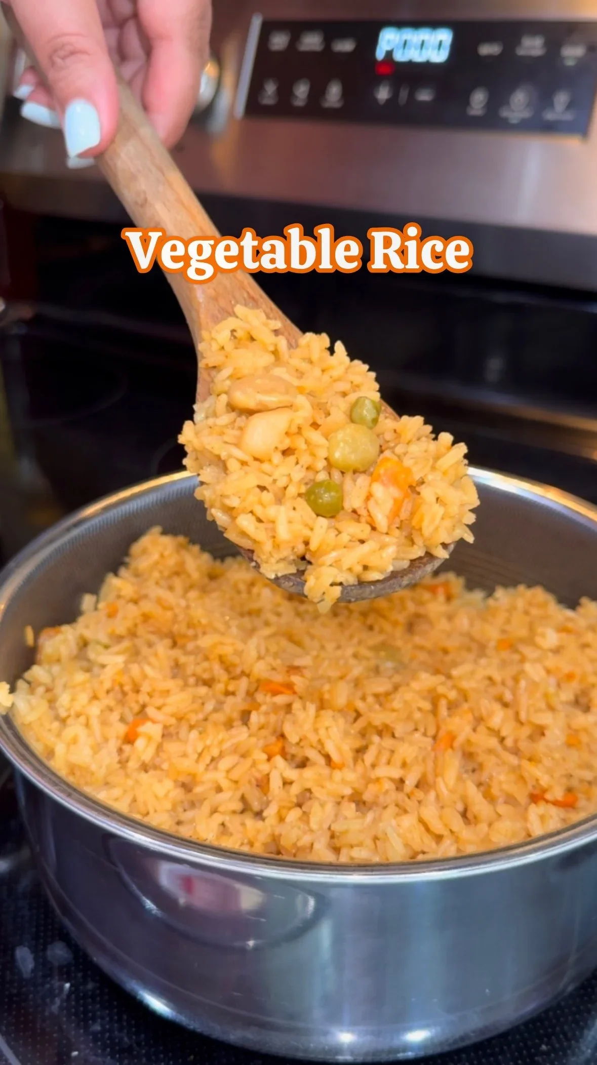 A pot of cooked vegetable rice being stirred with a wooden spoon, with a hand holding the spoon above the pot, and a stove in the background.
