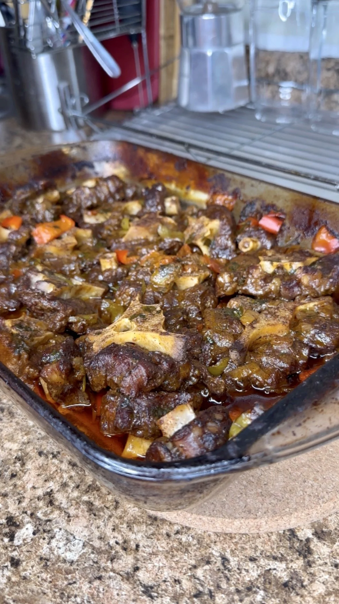 Beef stew with vegetables in a glass baking dish on a kitchen countertop.
