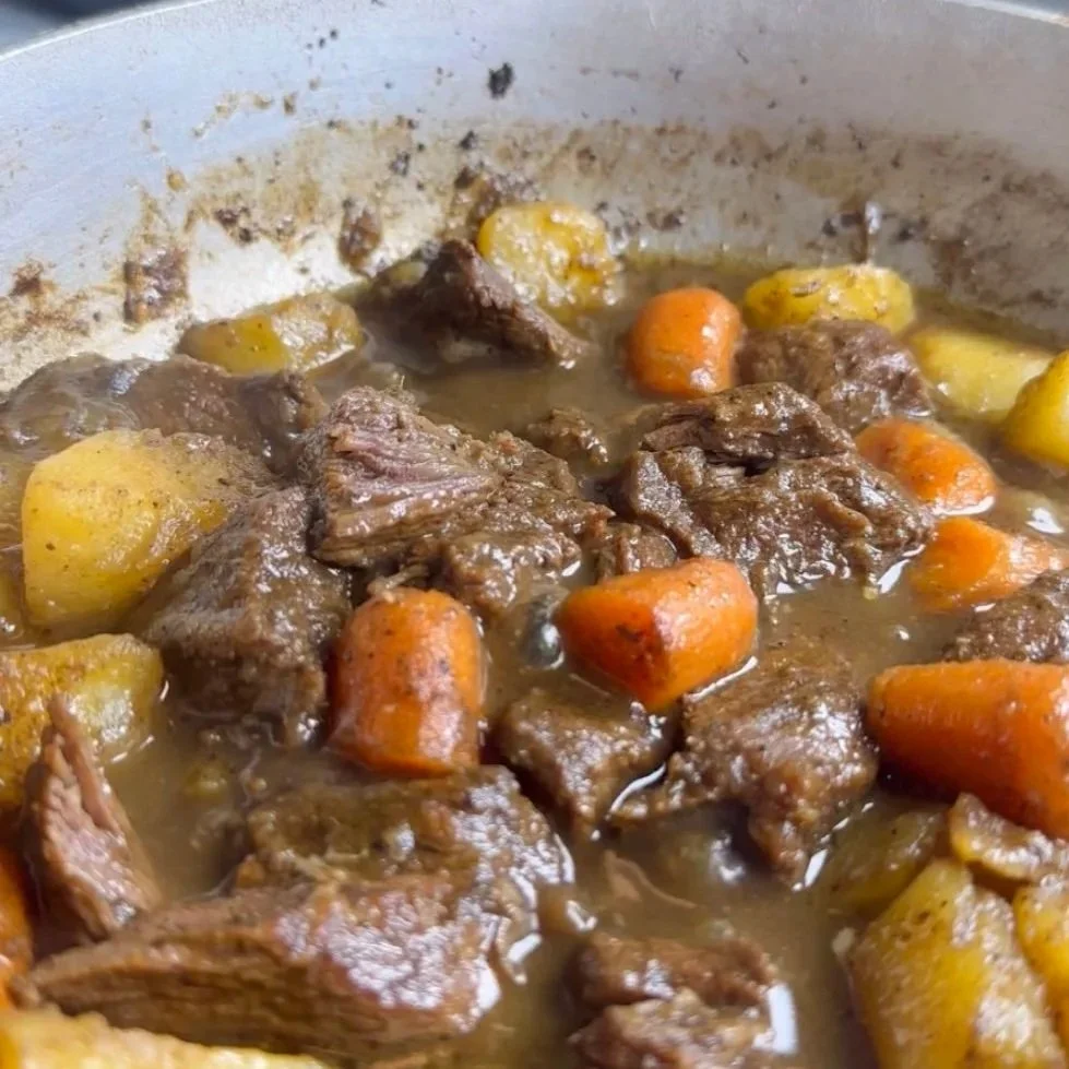 Beef stew with chunks of beef, potatoes, carrots, and yellow vegetables in a broth