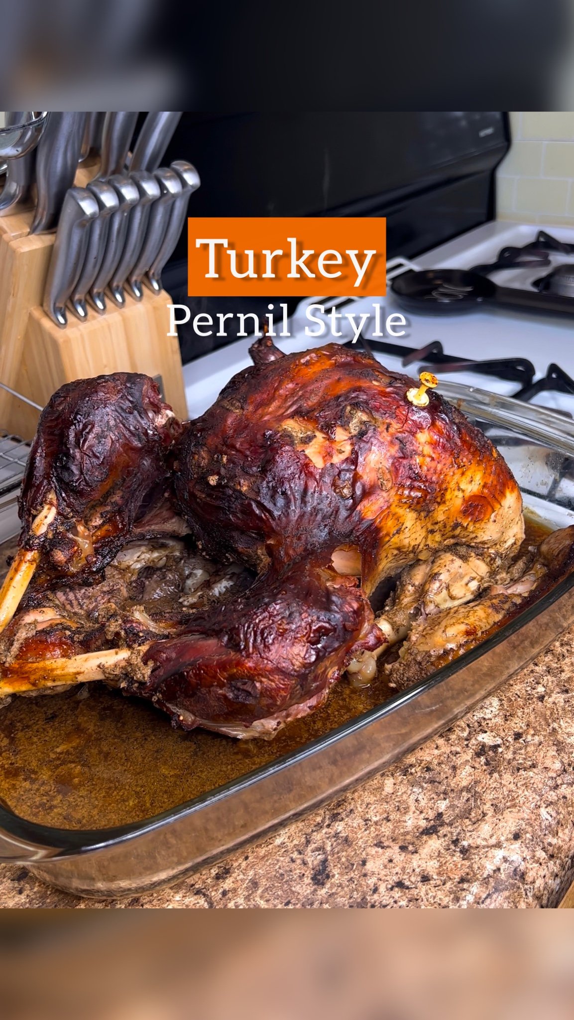 Baked whole turkey in a glass baking dish on a kitchen countertop, with a label indicating Turkey Pernil Style.