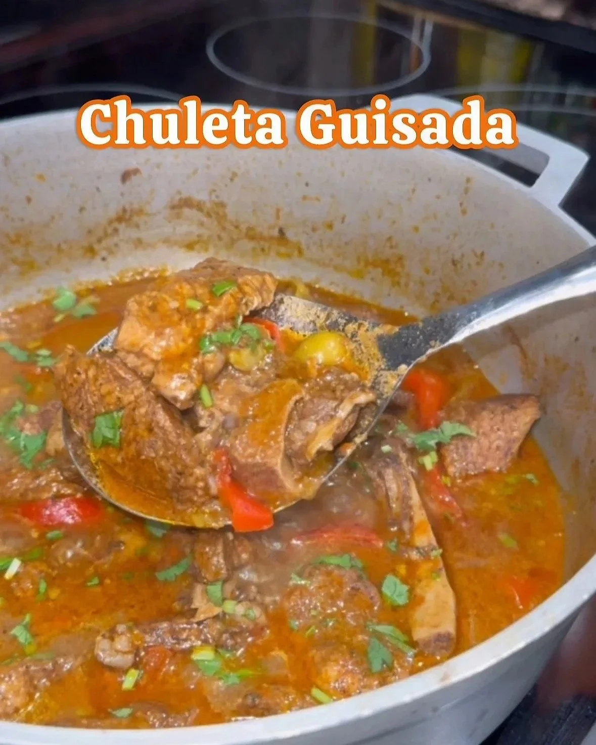 A pot of stewed pork chops, red peppers, and cilantro.