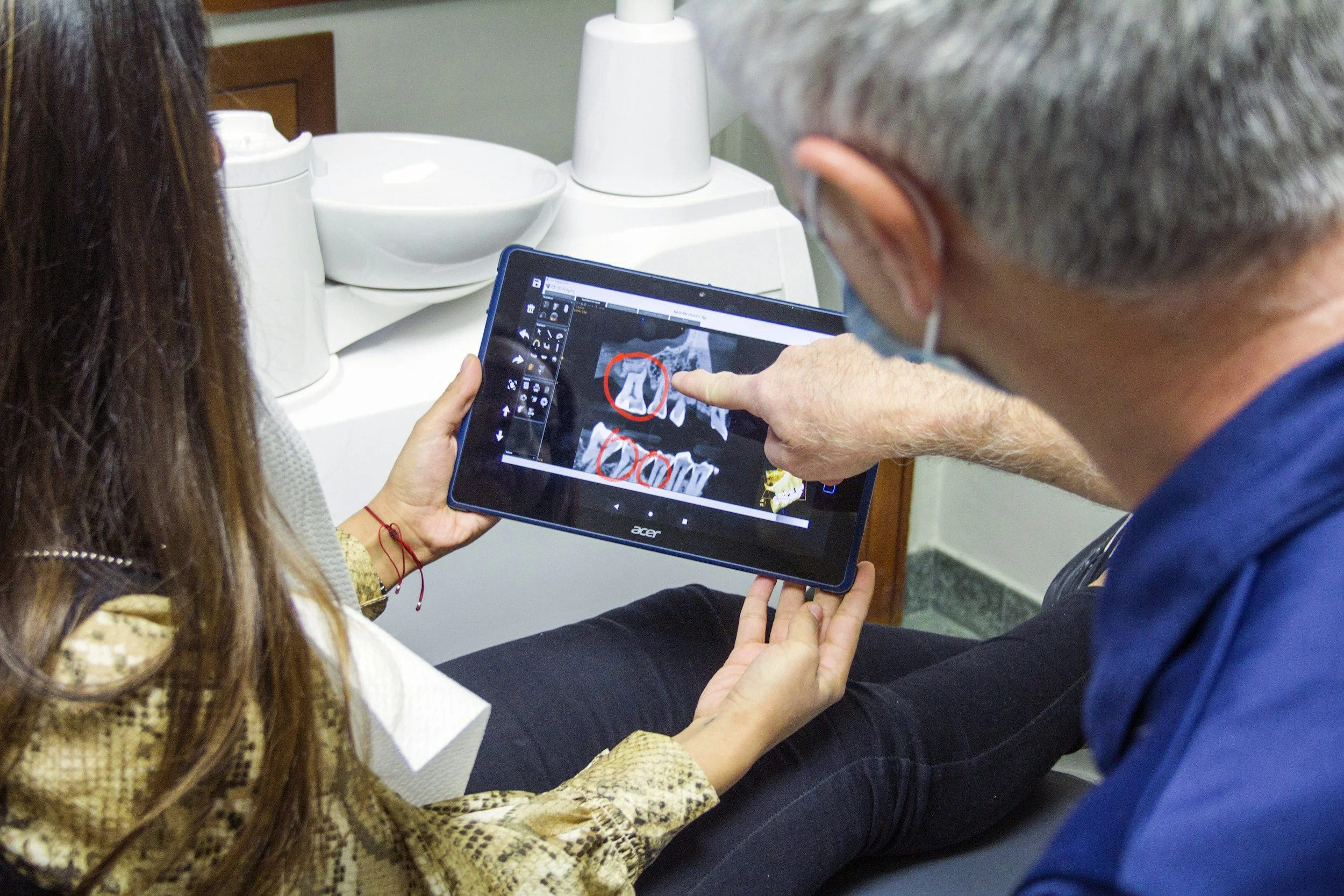 Doctor explaining dental X-ray to a patient using a tablet.