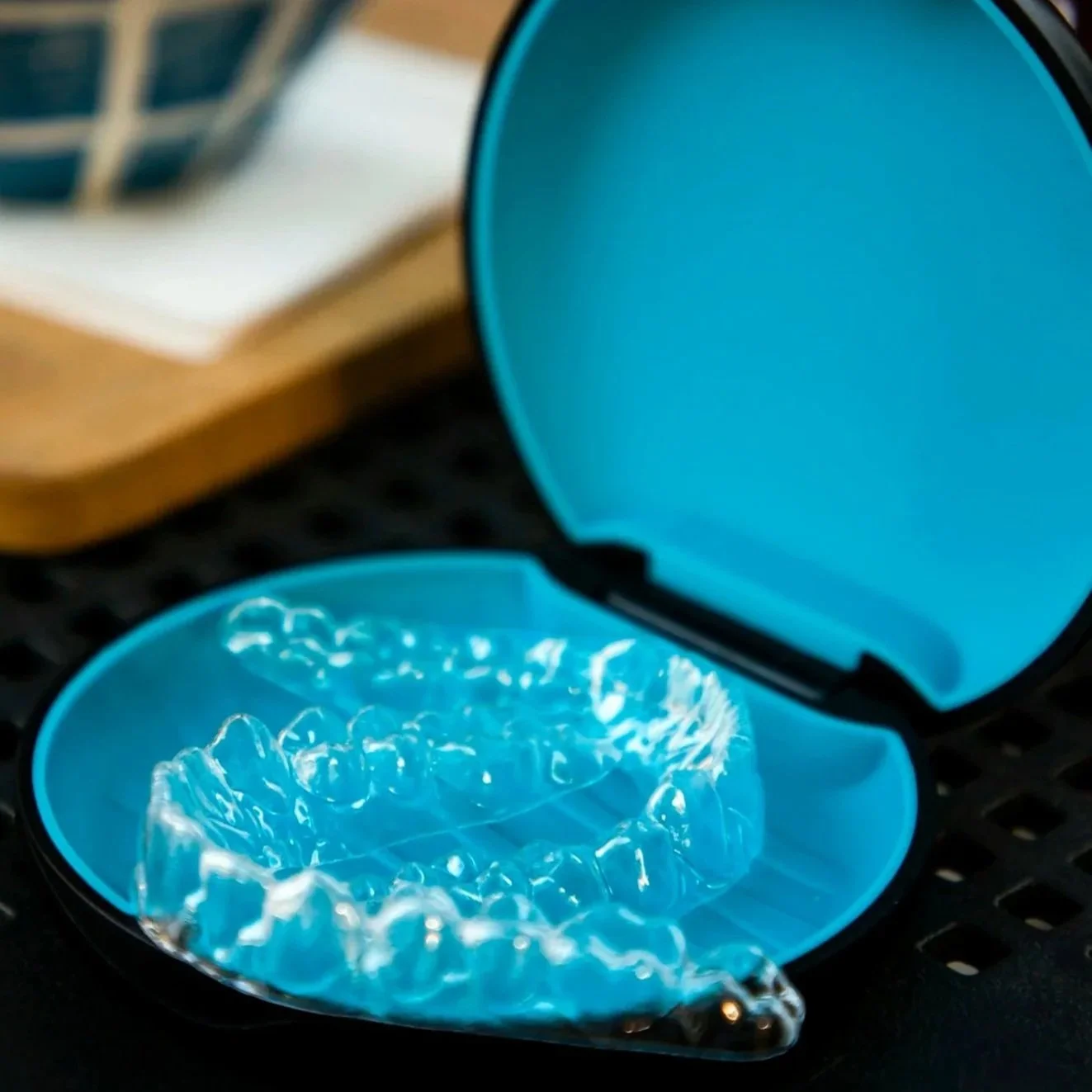 Clear transparent dental aligners inside a blue plastic case with an open lid.
