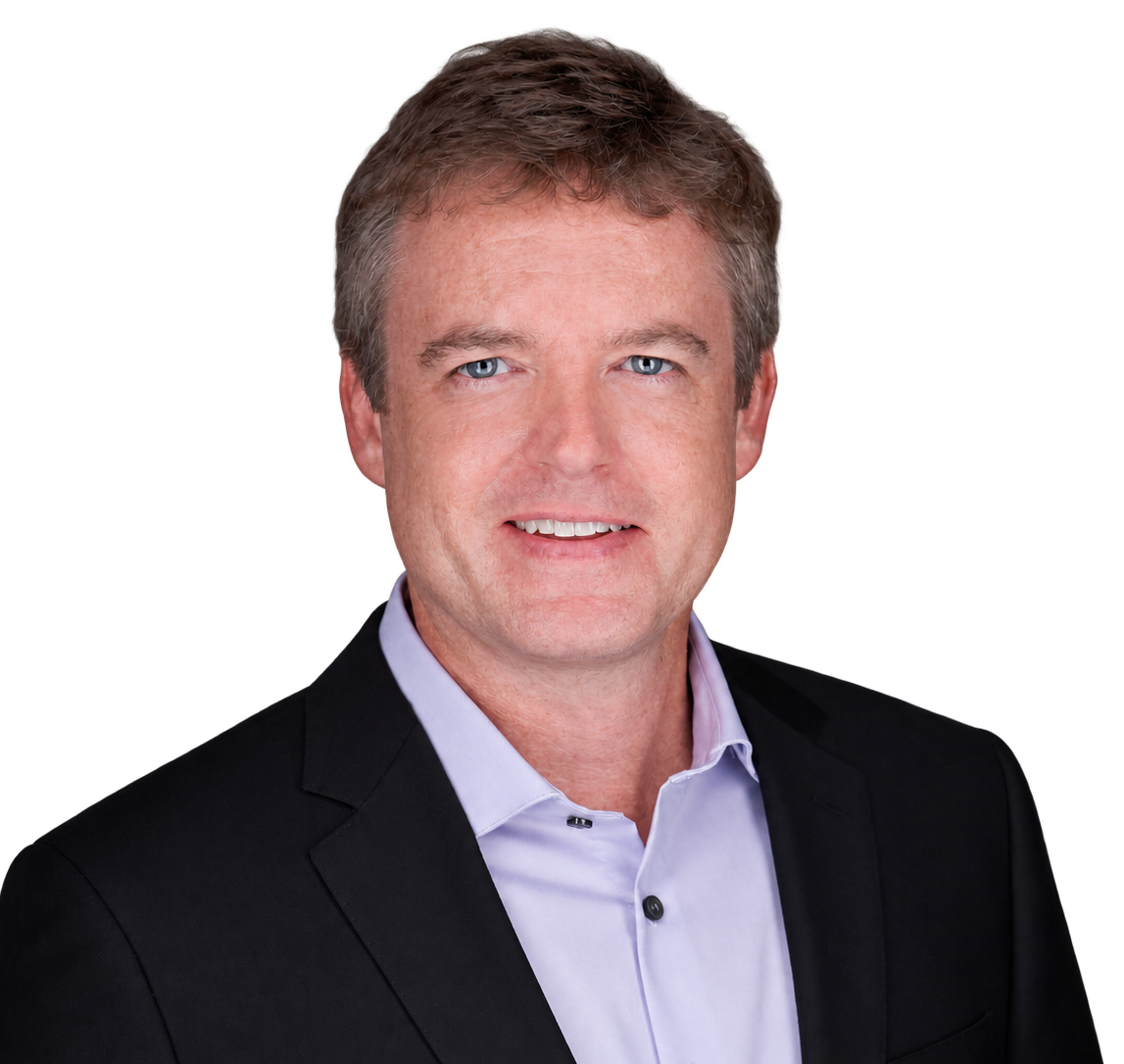 Ryan Douglas with short light brown hair, blue eyes, wearing a dark suit jacket and a light purple dress shirt, smiling slightly.