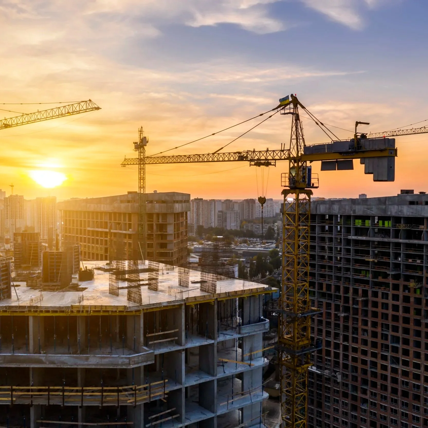 Commercial construction site with cranes and partially completed buildings.
