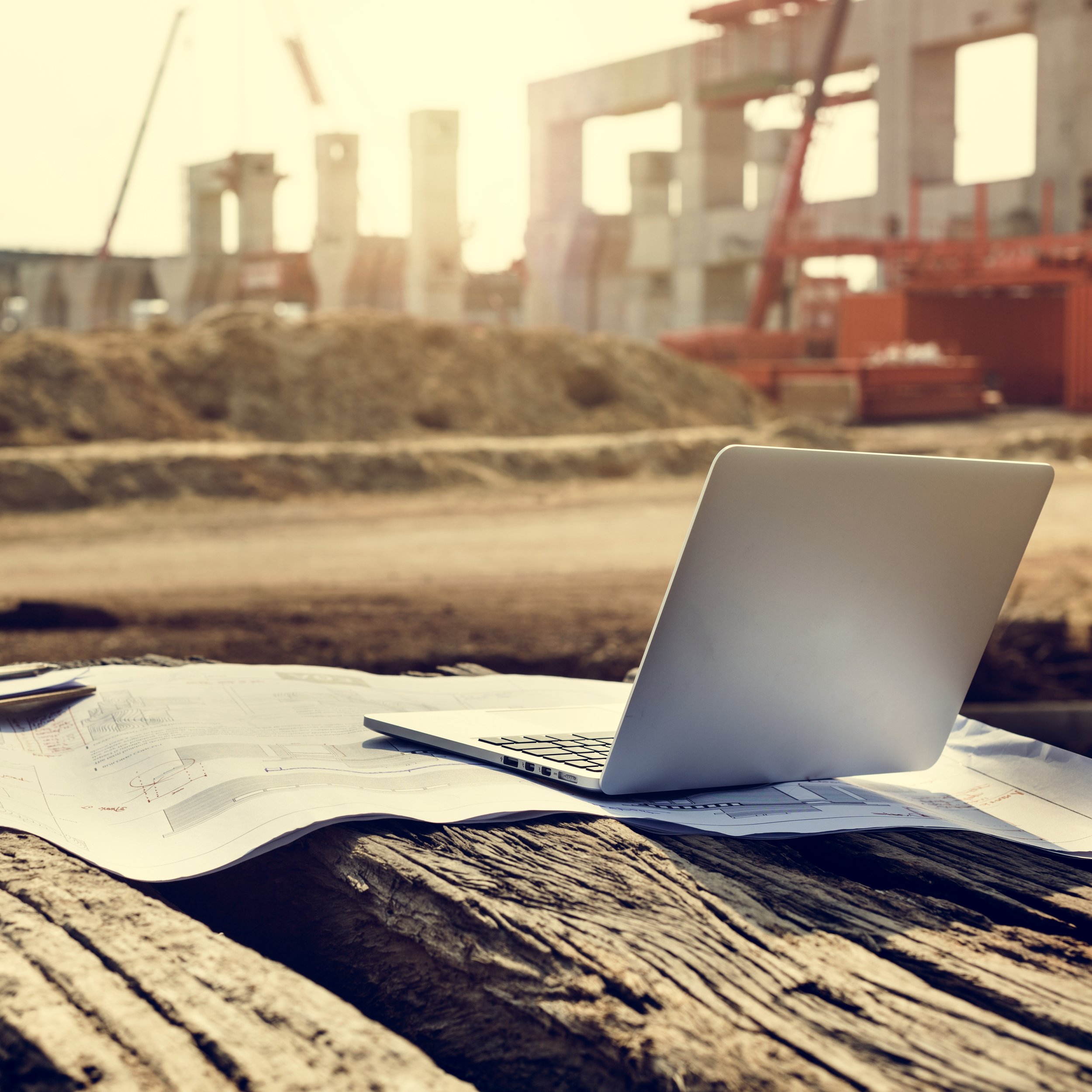 Architectural plans and laptop at an active construction project site.