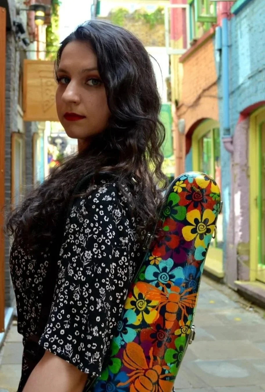 Katy Smith violinist holding her violin case in a colourful street