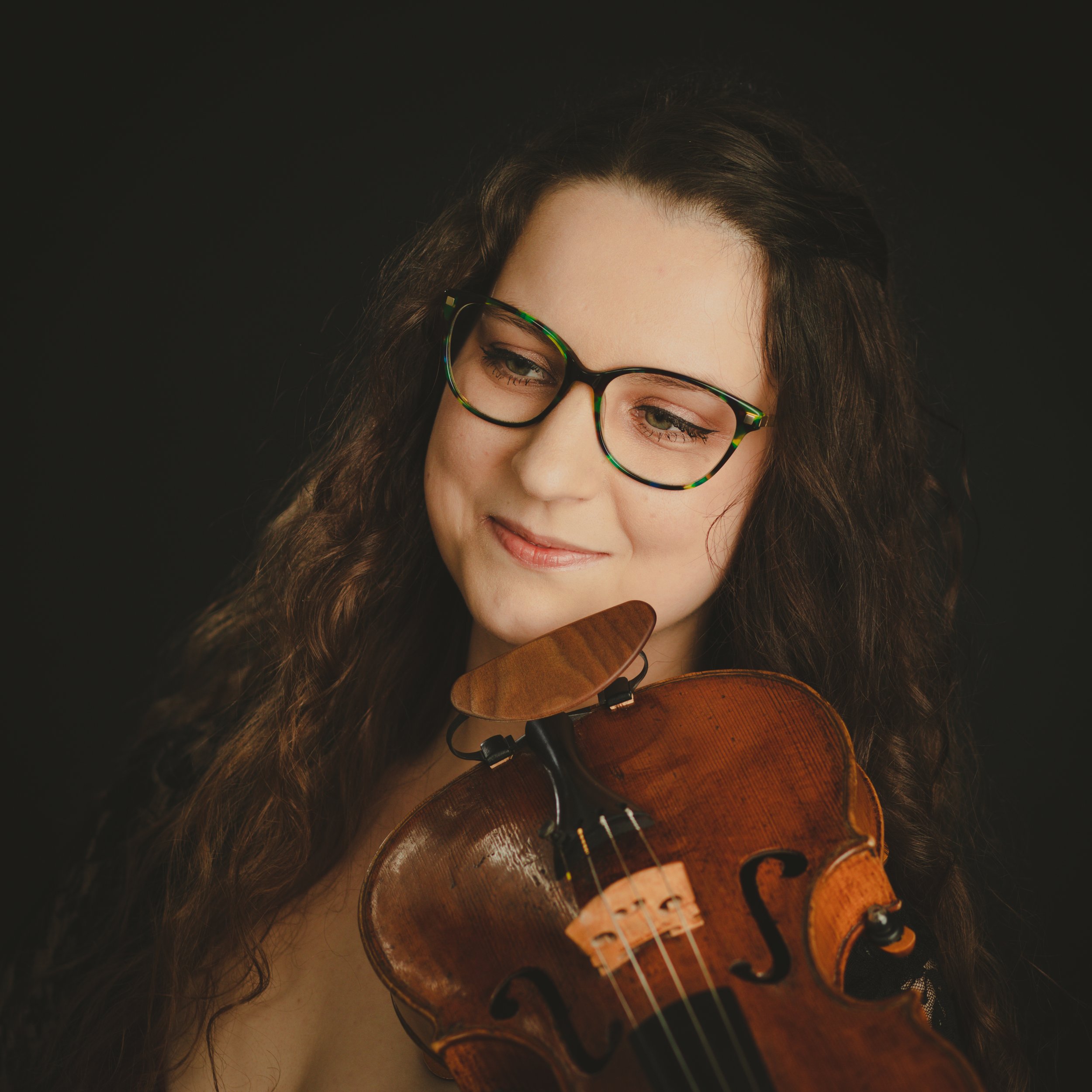 Studio photo of Violinist Katy Smith smiling with violin under chin relaxed.