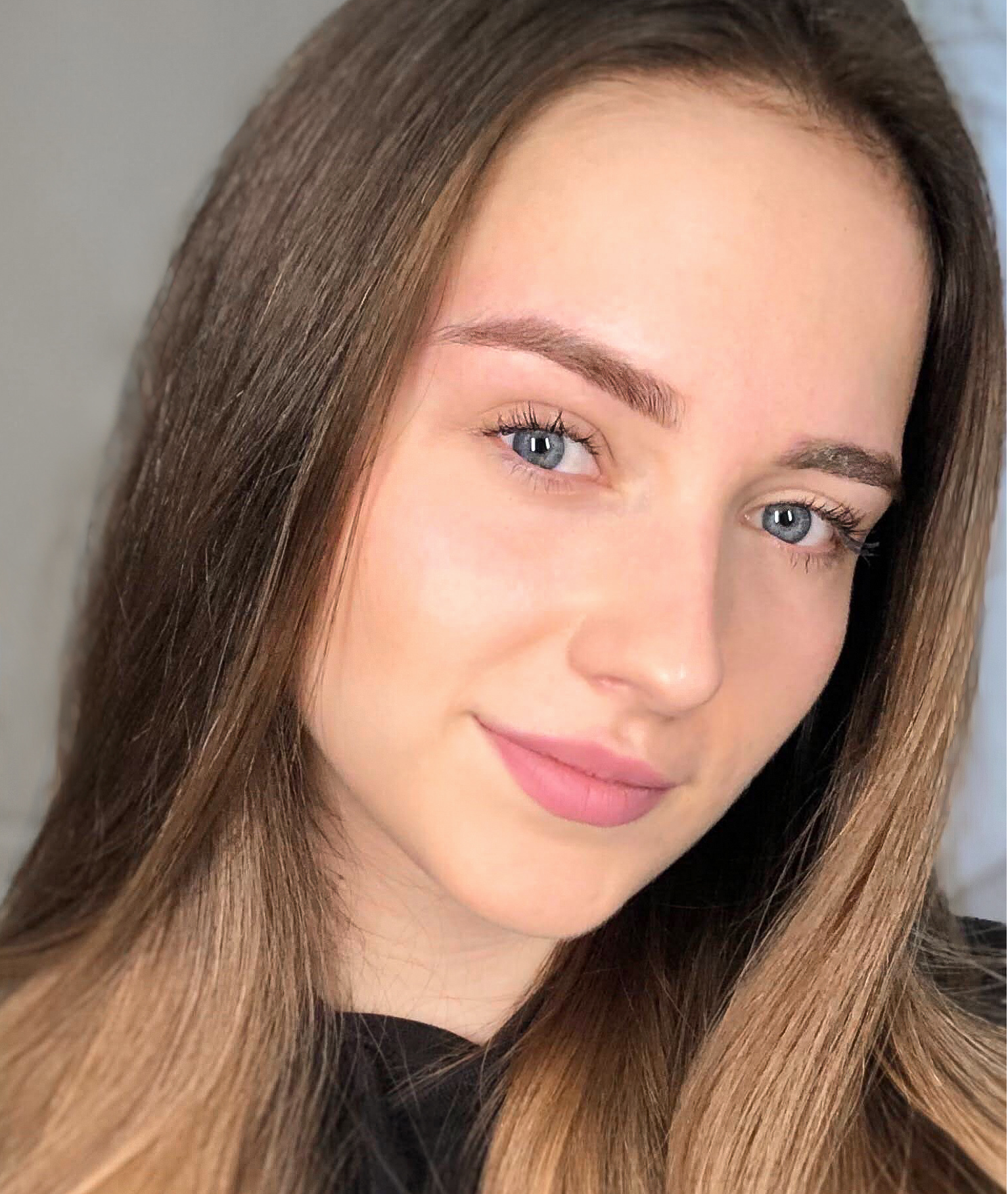 A young woman with long brown hair and blue eyes smiling gently.
