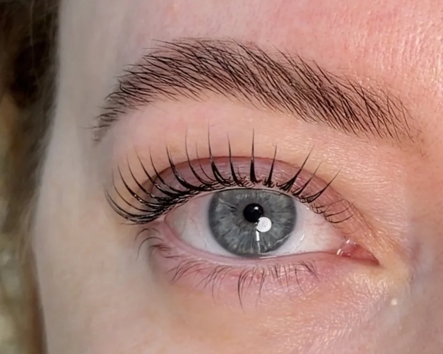 Close-up of a human eye with well-groomed eyebrow, long eyelashes, and grayish-blue iris.