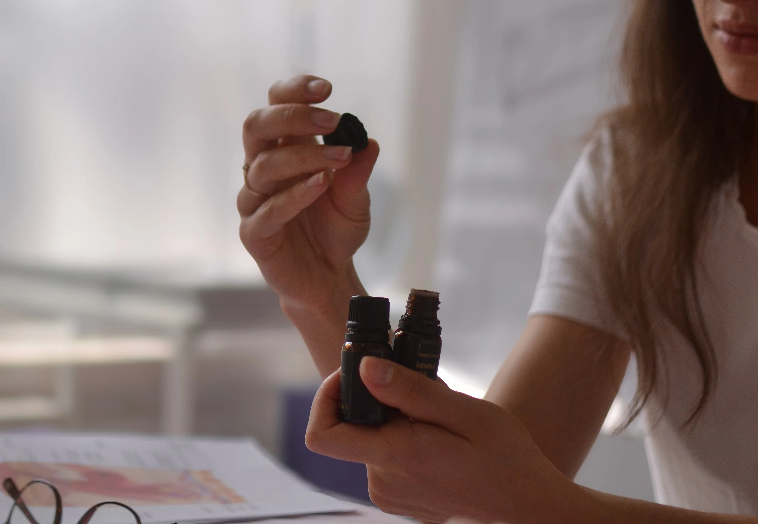 A person holding a small container and a dropper bottle, about to take some liquid