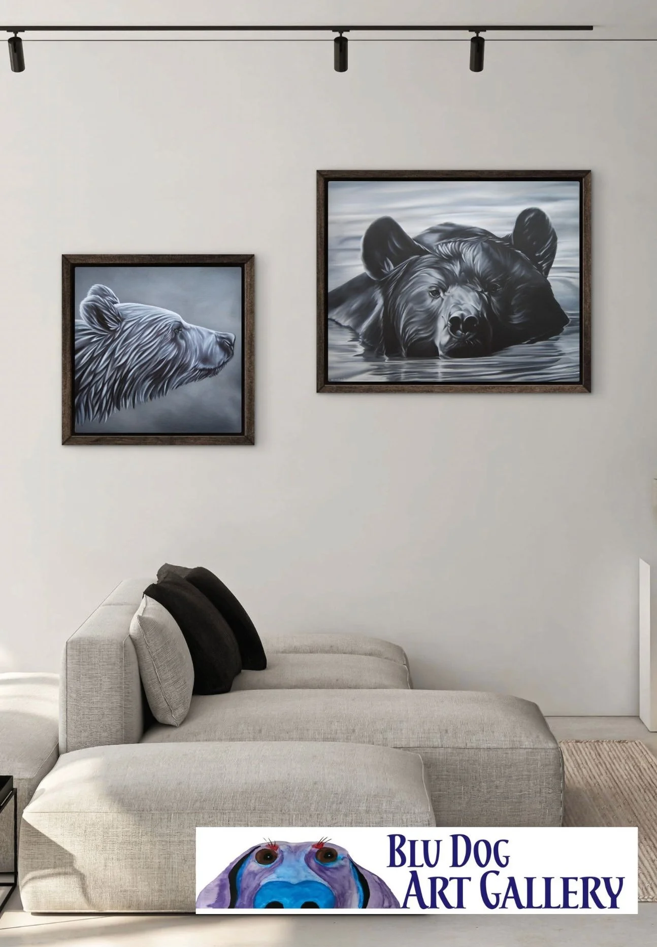 Interior of a modern living room with two black and white paintings of bears on a white wall above a beige sofa with black pillows. There's a track lighting fixture on the ceiling and a logo for Blu Dog Art Gallery at the bottom.