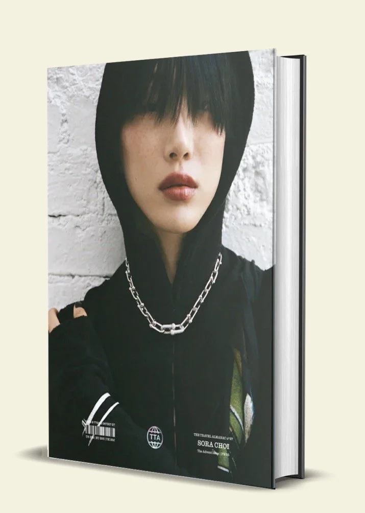 Book cover featuring a woman with black hair in a hoodie, standing against a white brick wall, wearing layered chains, with text indicating it's by Sora Choi.