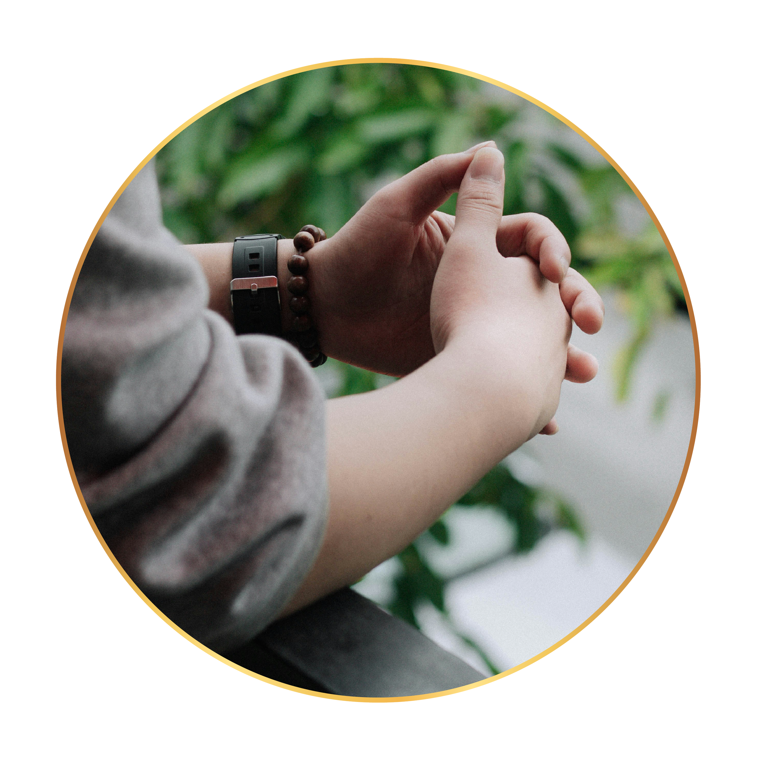 Close-up of a person leaning against a railing with hands clasped, while outdoors with green foliage in the background.