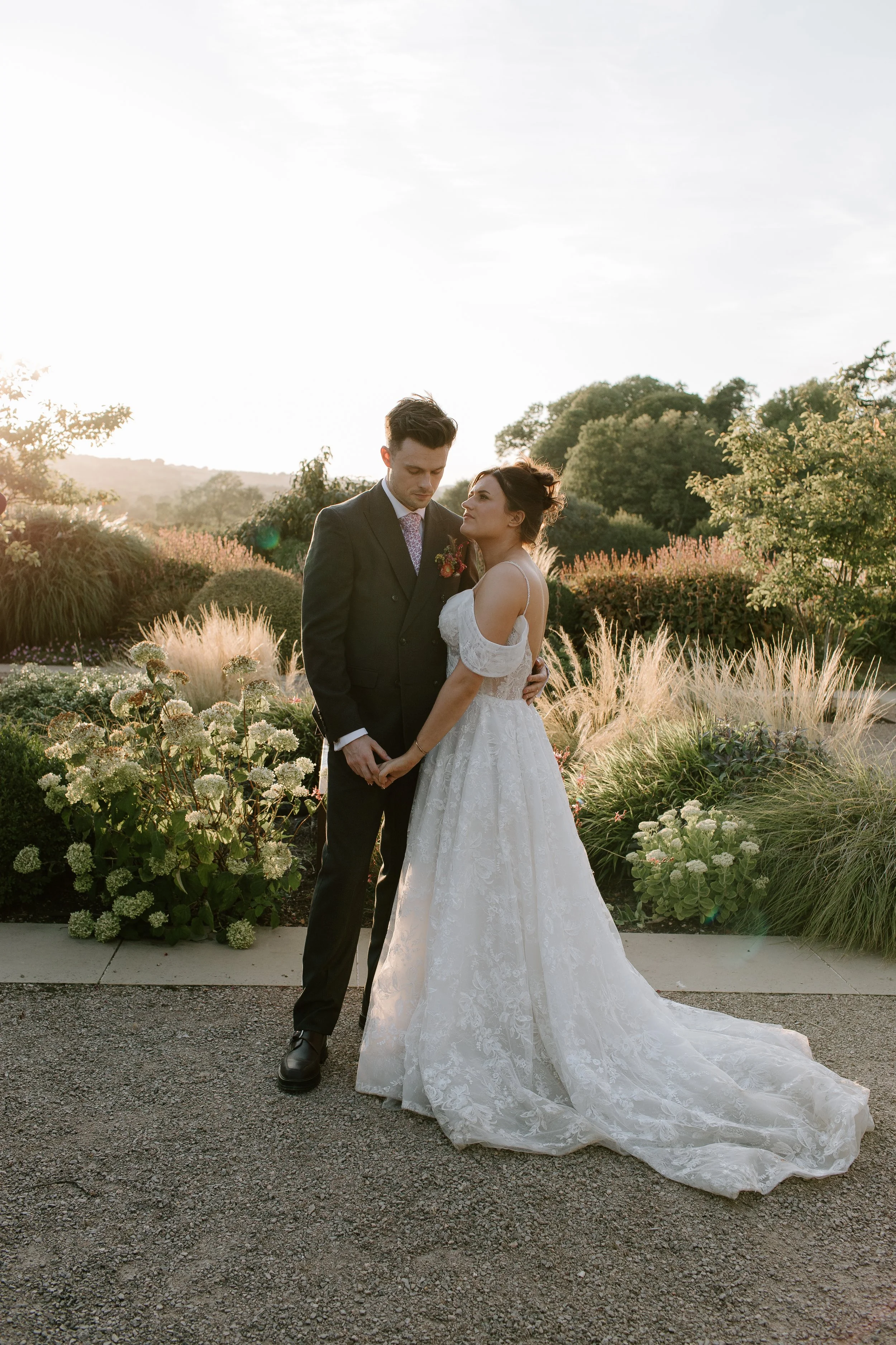 Golden hour wedding photography at Hyde House in Somerset showing a bride and groom holding hands in the gardens.