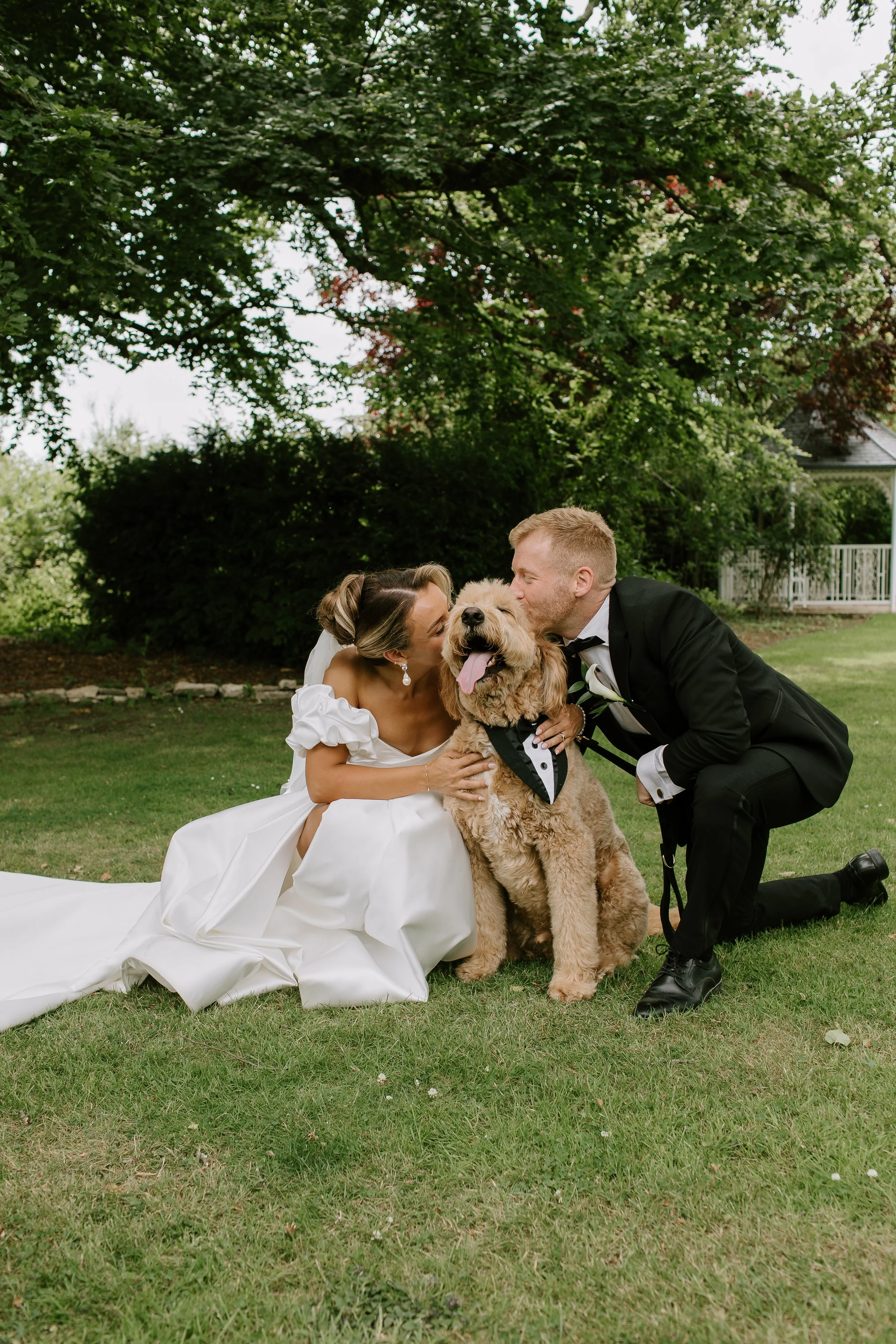 Bride and groom kneeling on the grass with their dog during a relaxed, pet-friendly wedding at a Somerset wedding venue.