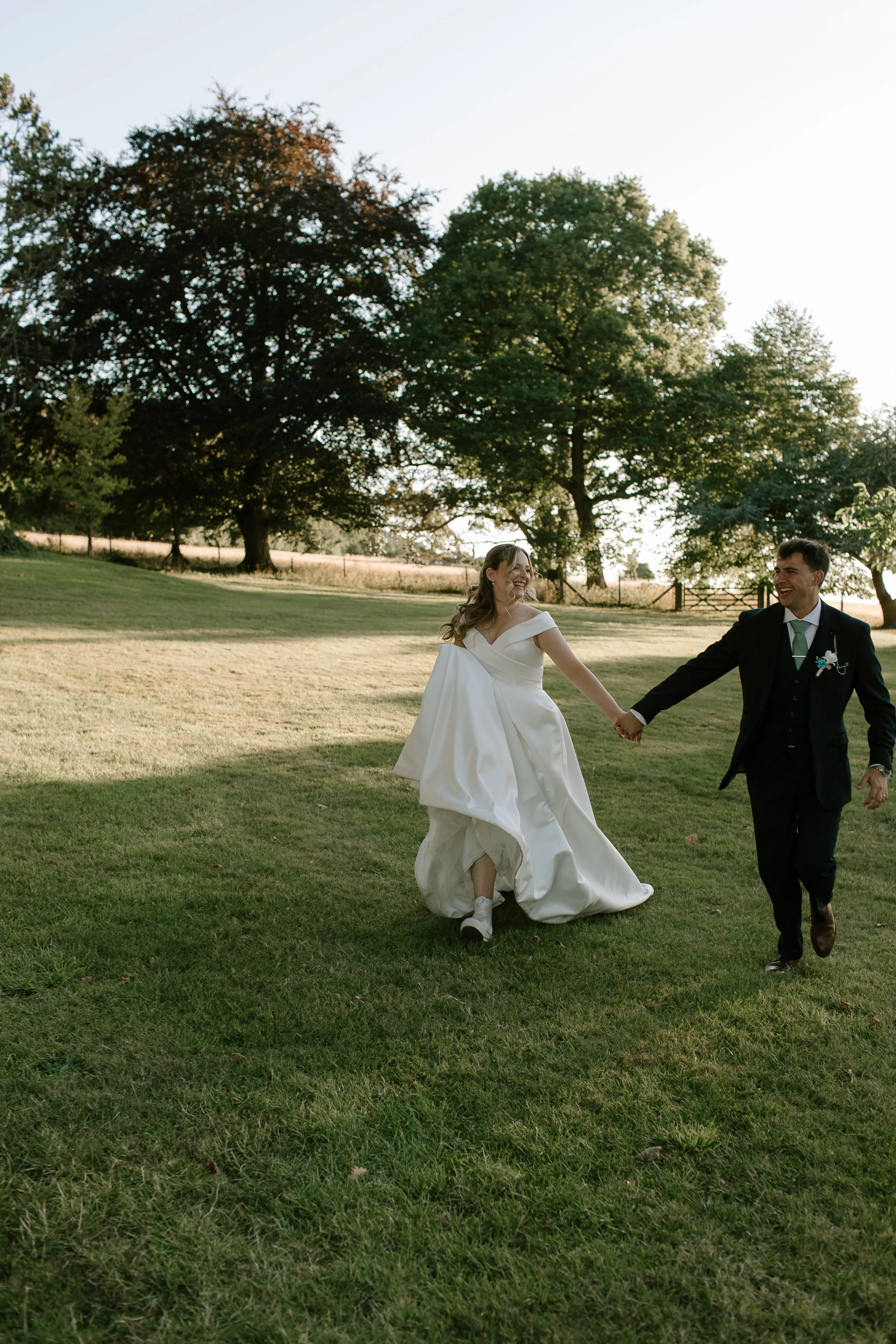 “Bride and groom running hand in hand across the lawn during relaxed wedding portraits at a Somerset wedding venue.