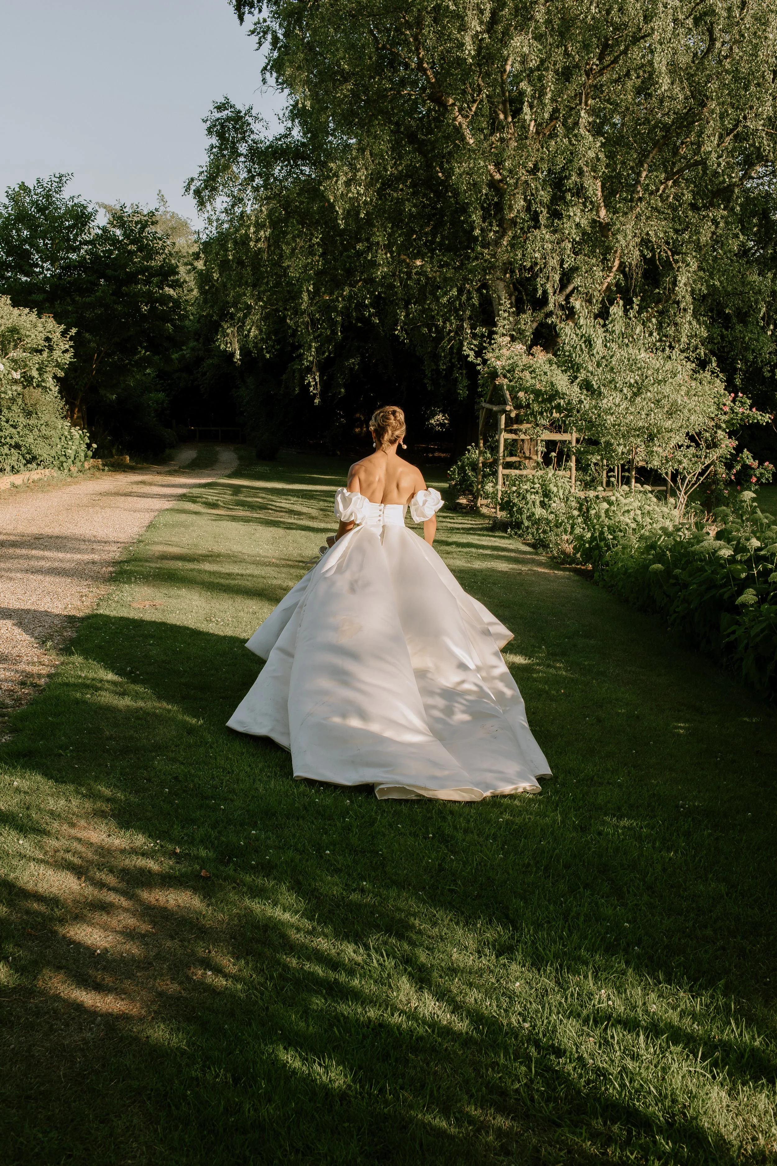 Bride walking through the gardens of a Somerset country house wedding venue during golden hour wedding portraits
