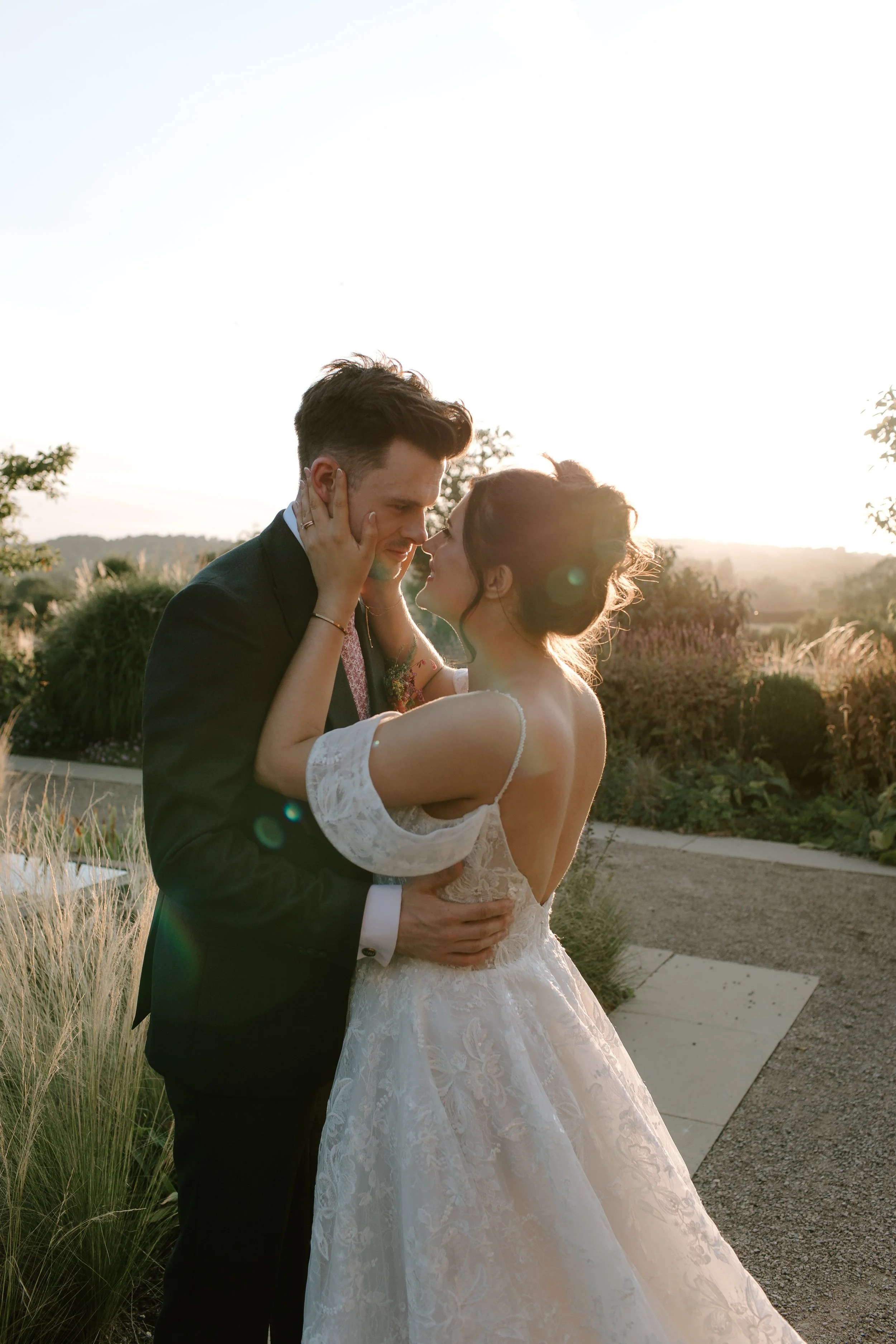 Bride and groom embracing during golden hour at Hyde House, surrounded by gardens on their Somerset wedding day.