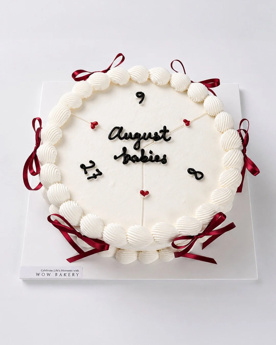Custom white fresh cream cake with burgundy ribbon details and a calendar-inspired design by WOW Bakery Calgary.