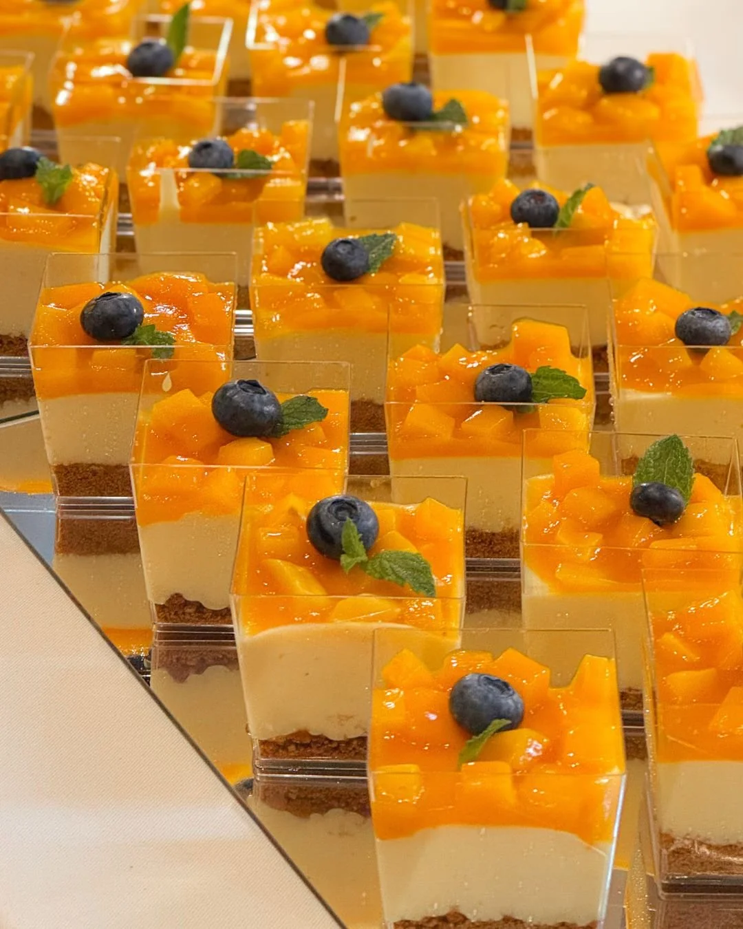 Mango mousse cups topped with fresh mango, blueberries, and mint on WOW Bakery’s wedding dessert table in Calgary