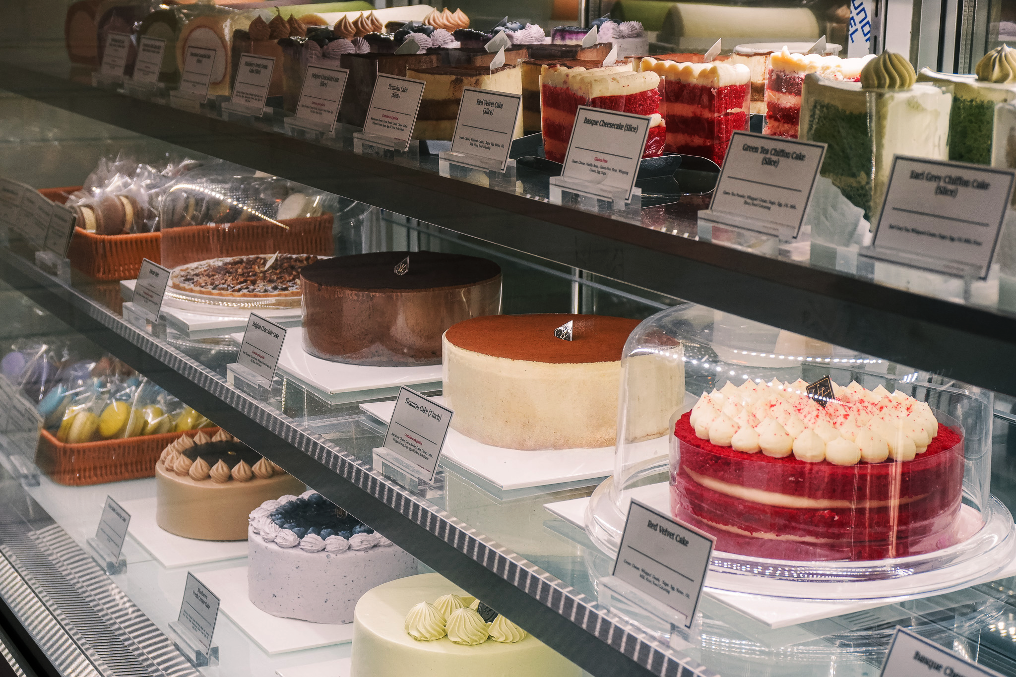 Assorted cakes including red velvet, tiramisu, and cheesecake displayed in the WOW Bakery cake showcase.