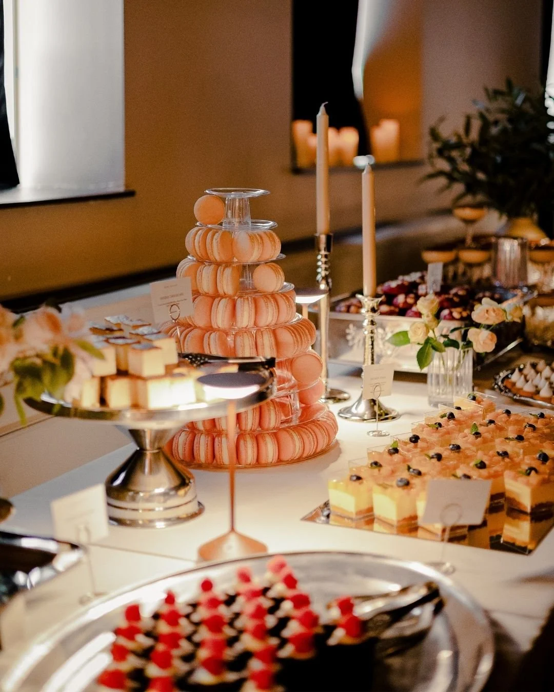 Wedding dessert table by WOW Bakery in Calgary featuring a pink macaron tower, cakes, and assorted bite-sized desserts