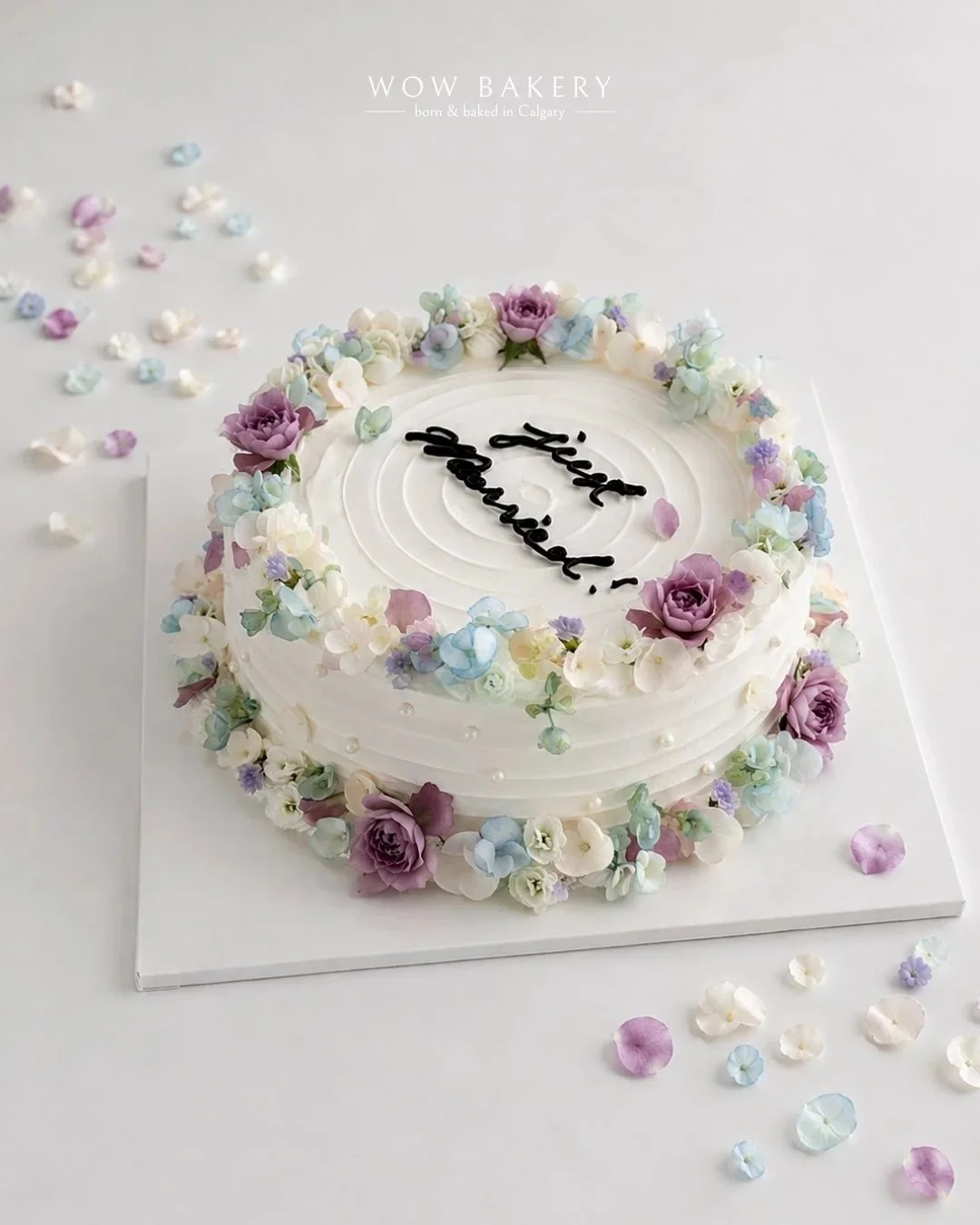Pastel floral Just Married cake with blue, lavender and white flowers by WOW Bakery in Calgary.