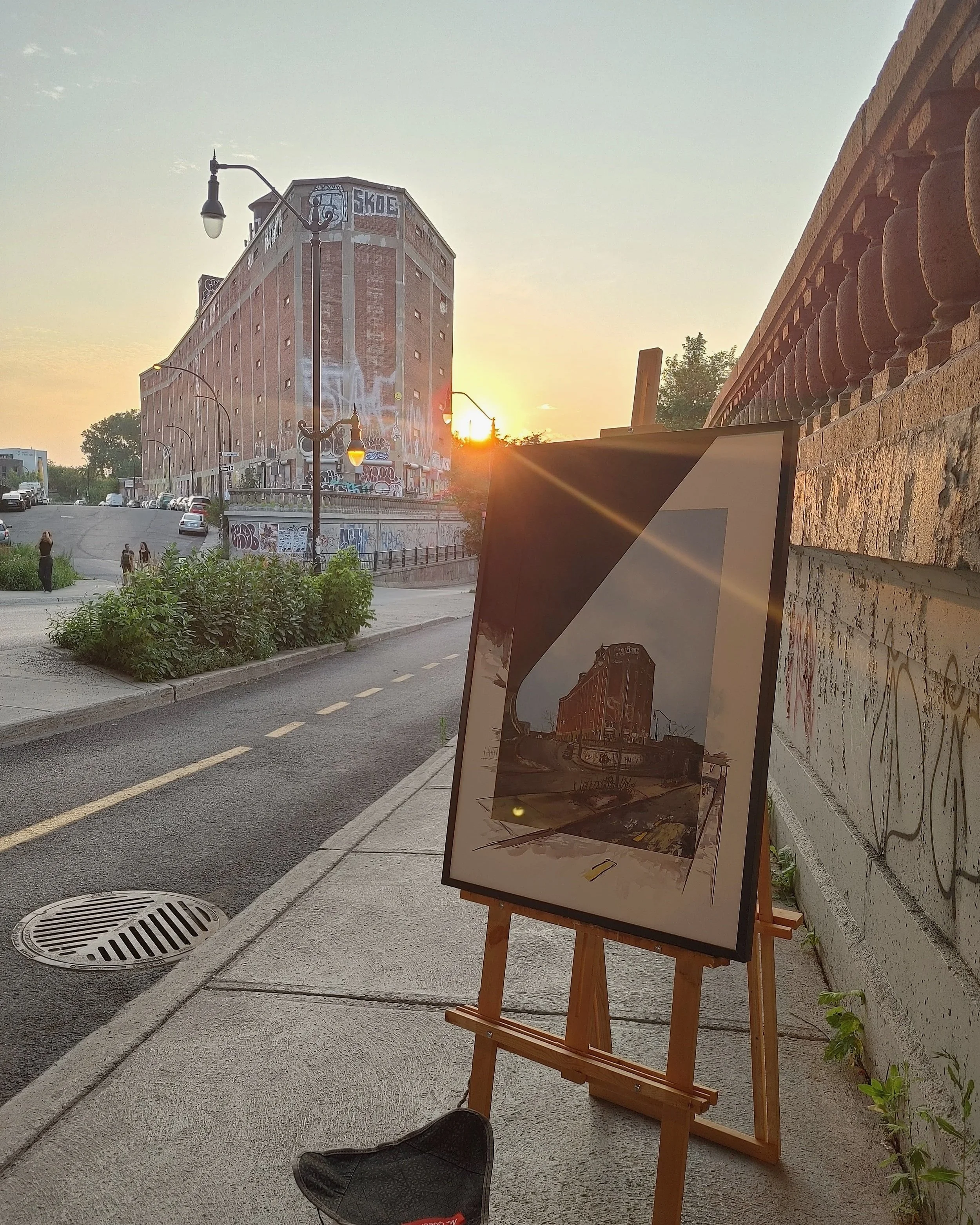 Easel with a large format reprensenting Van Horne Warehouse, which is in the back at sunset.