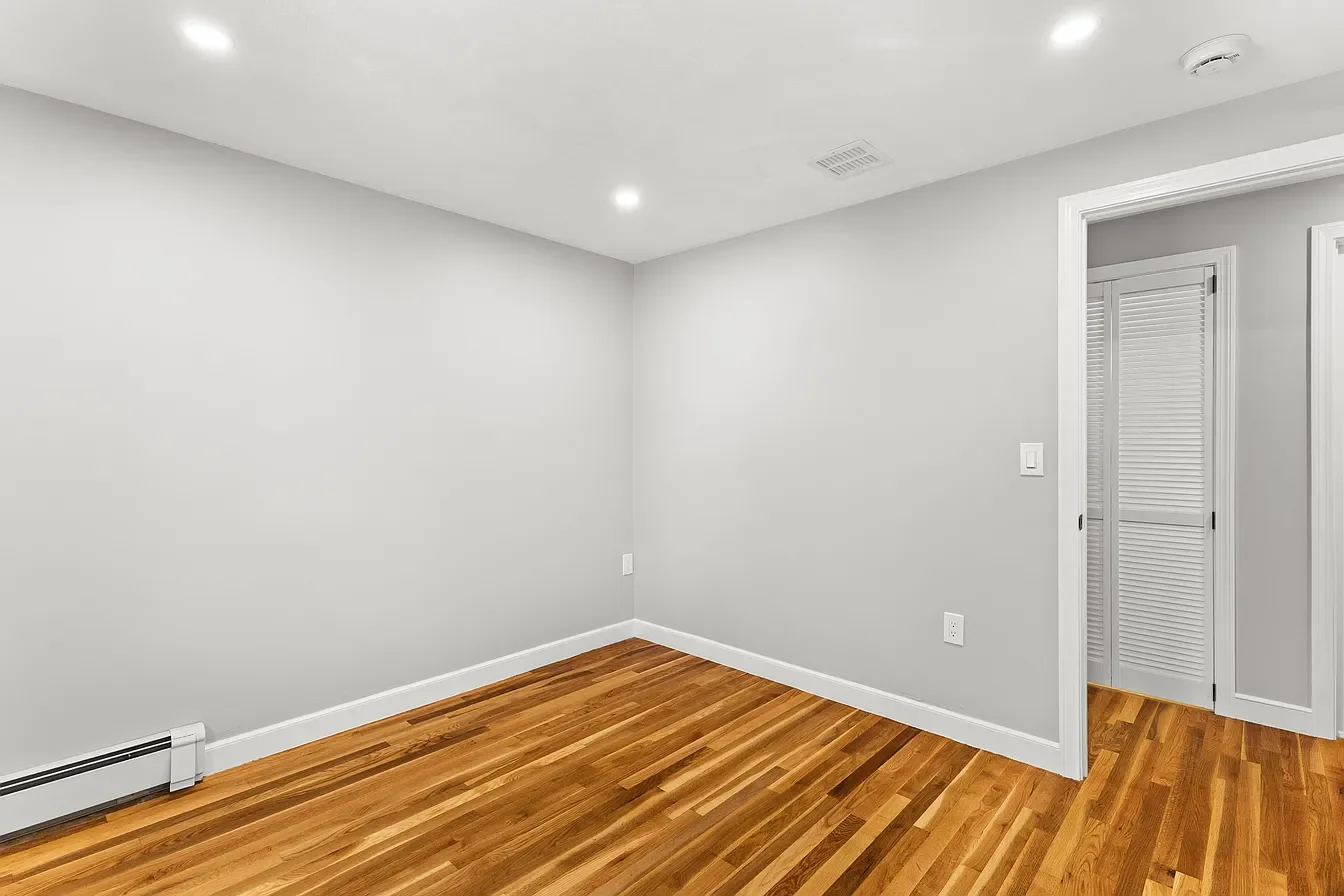 Empty room with white walls, hardwood floor, and walk-in closet door.