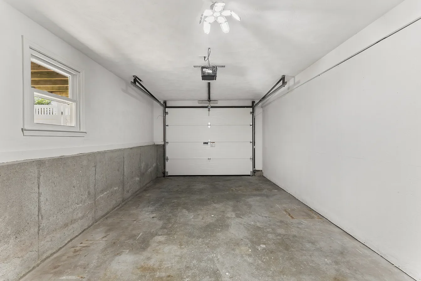 Empty garage with concrete floor, white walls, a window, and a closed garage door.