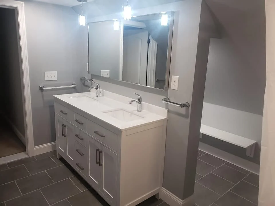 Bathroom vanity with double sink, large mirror, and gray tiled floor.