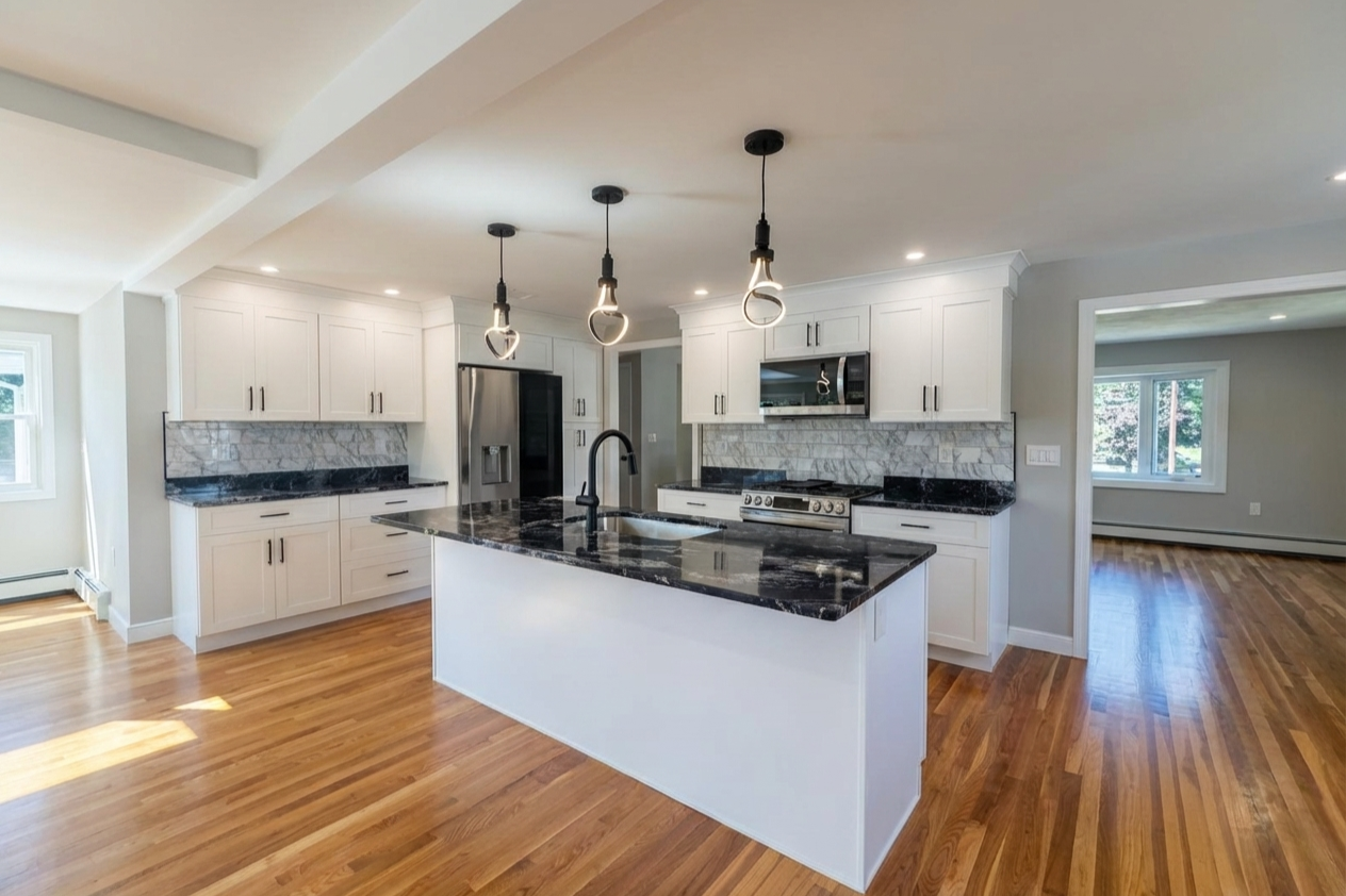 Modern kitchen with white cabinets, black granite countertops, marble backsplash, stainless steel appliances, and hardwood floors, illuminated with pendant lights and natural light.