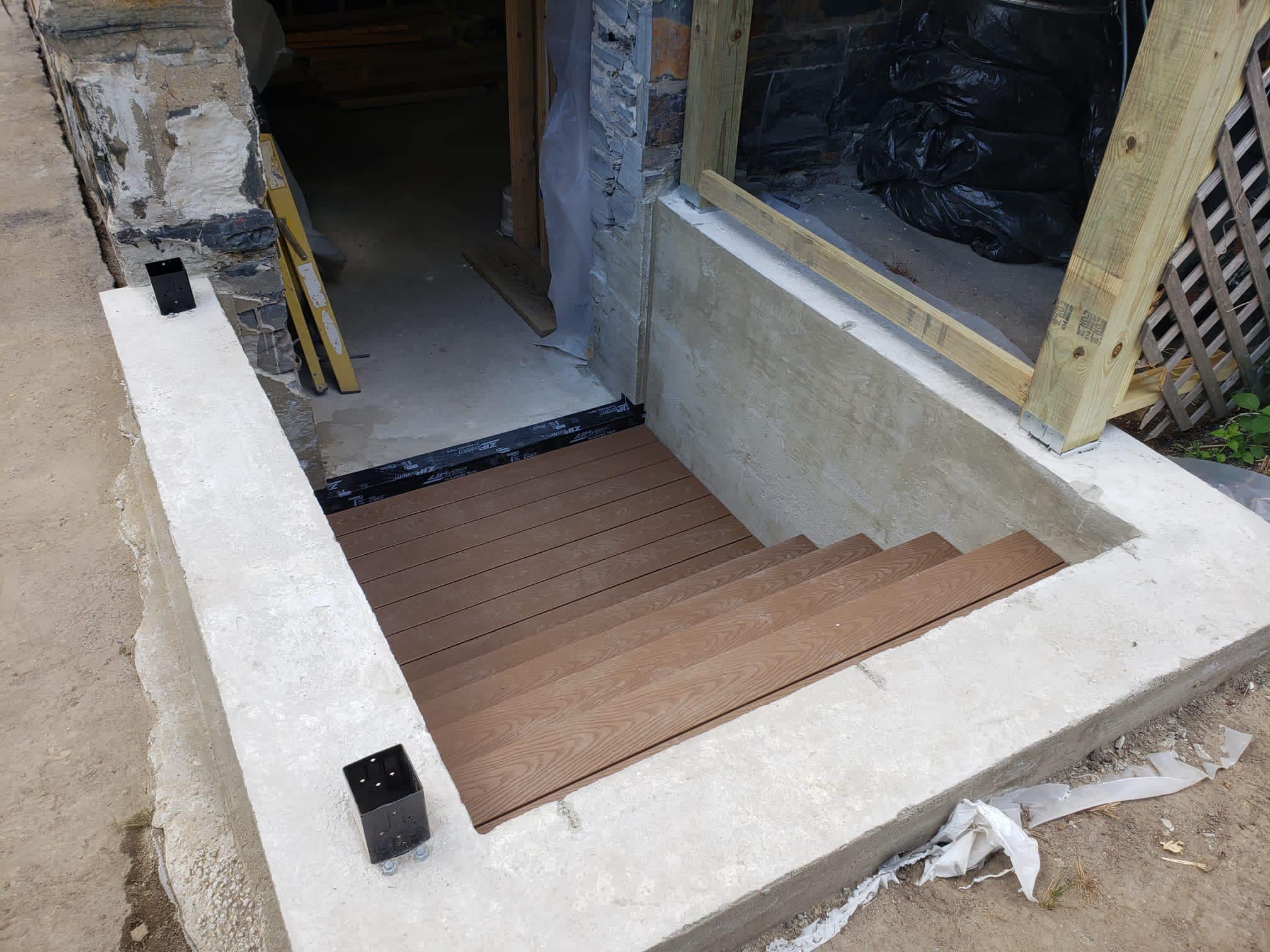 Construction site with concrete staircase and wooden steps being installed.