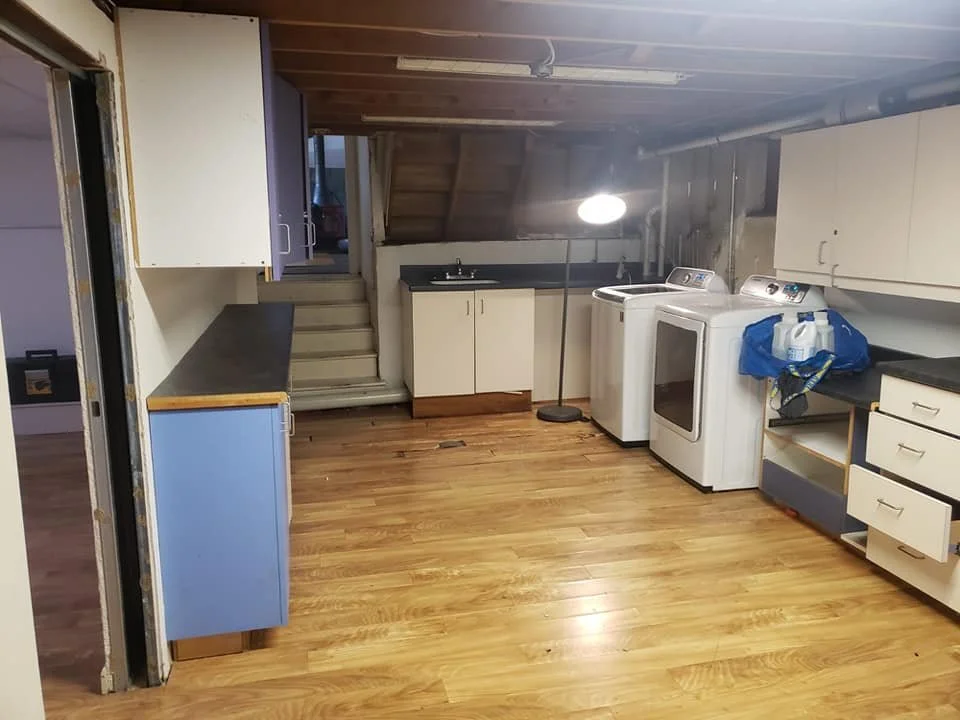Laundry room with washer and dryer, cabinets, countertop, sink, and a lamp on a wooden floor.