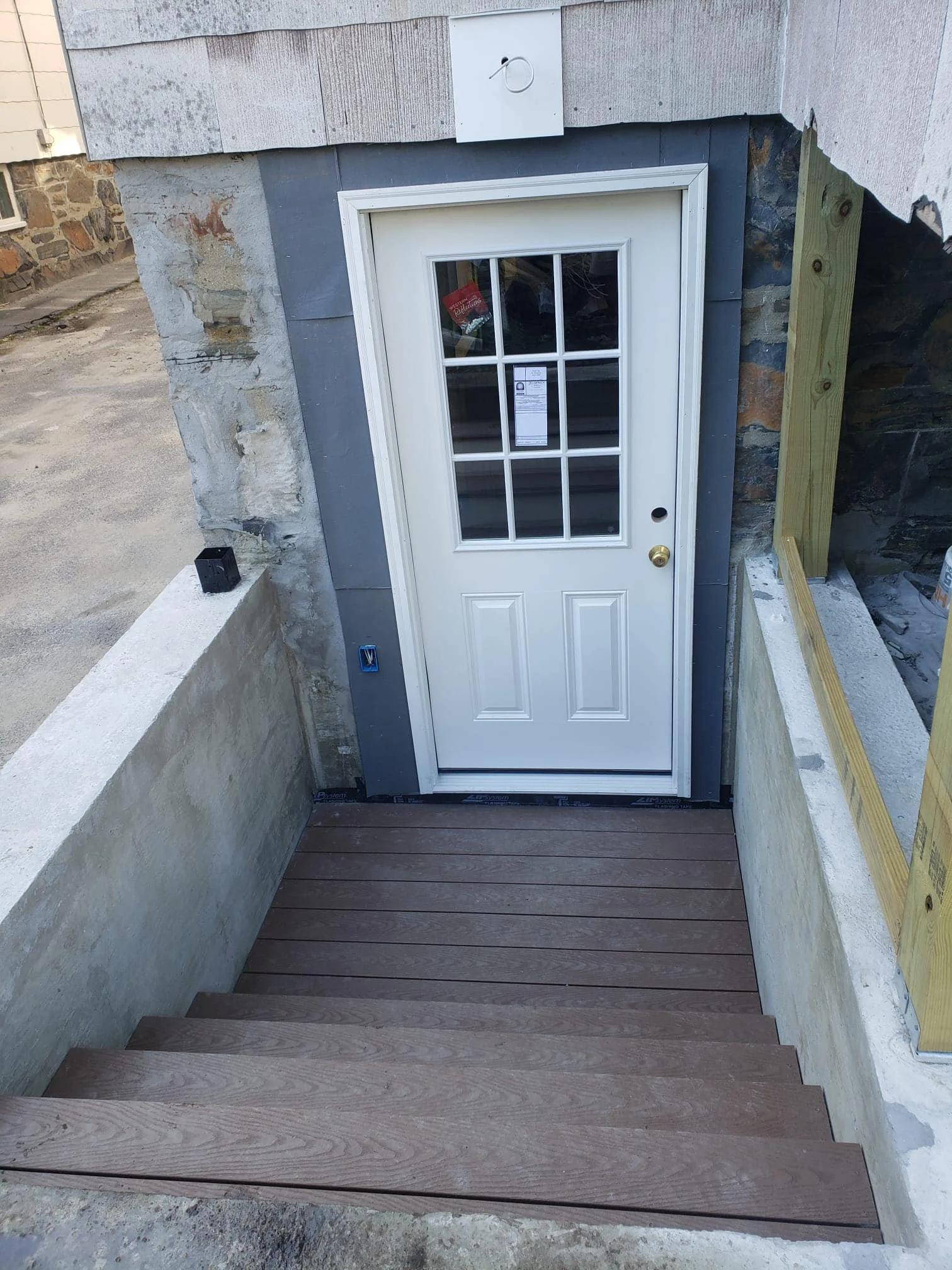 Exterior view of a white door with glass panels, set in a construction area with stairs leading down.