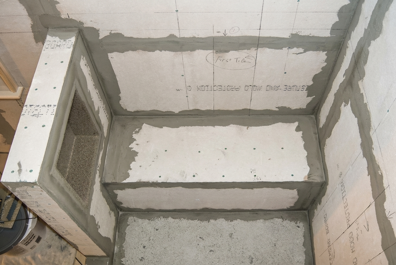 Interior of a building under construction, showing partially built walls with cement and drywall, and a HVAC vent opening.