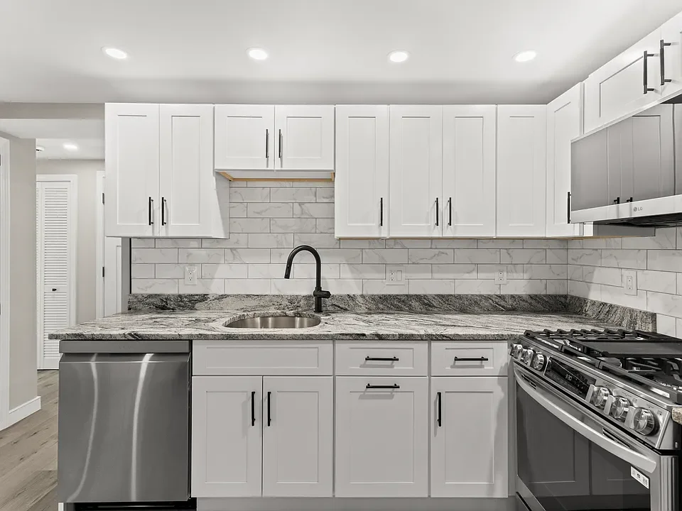 Modern kitchen with white cabinets, granite countertops, stainless steel sink, and a gas stove.