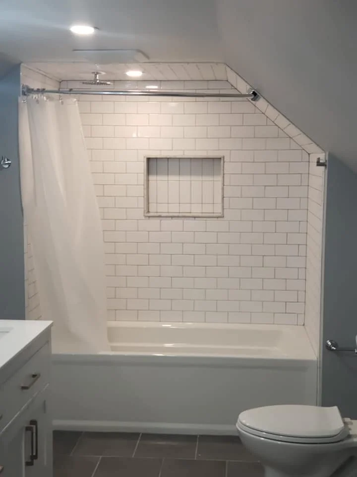 Bathroom with white bathtub, white subway tile wall, small window, white shower curtain, gray walls, and a toilet.