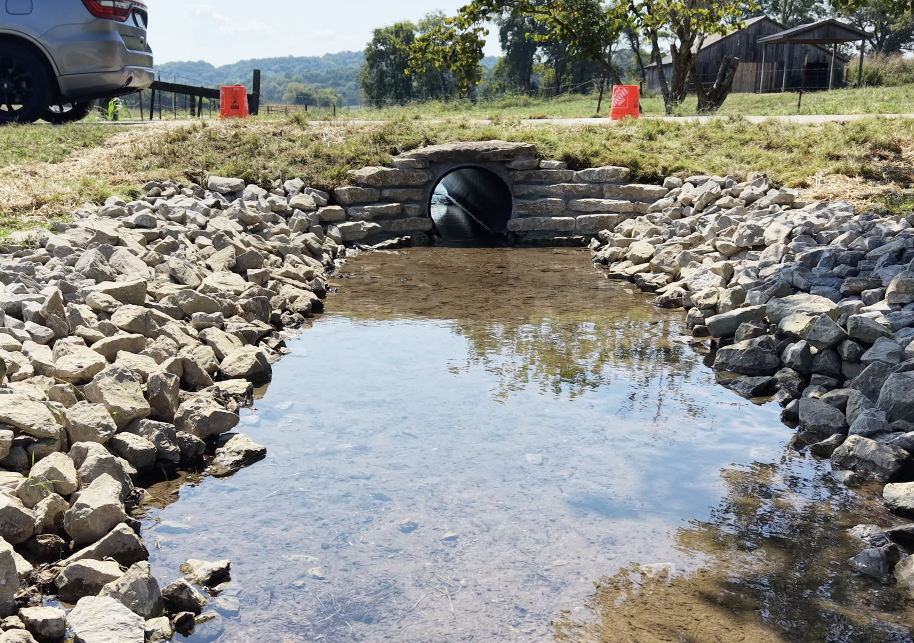 Drainage creek flowing into a culvert beneath a driveway