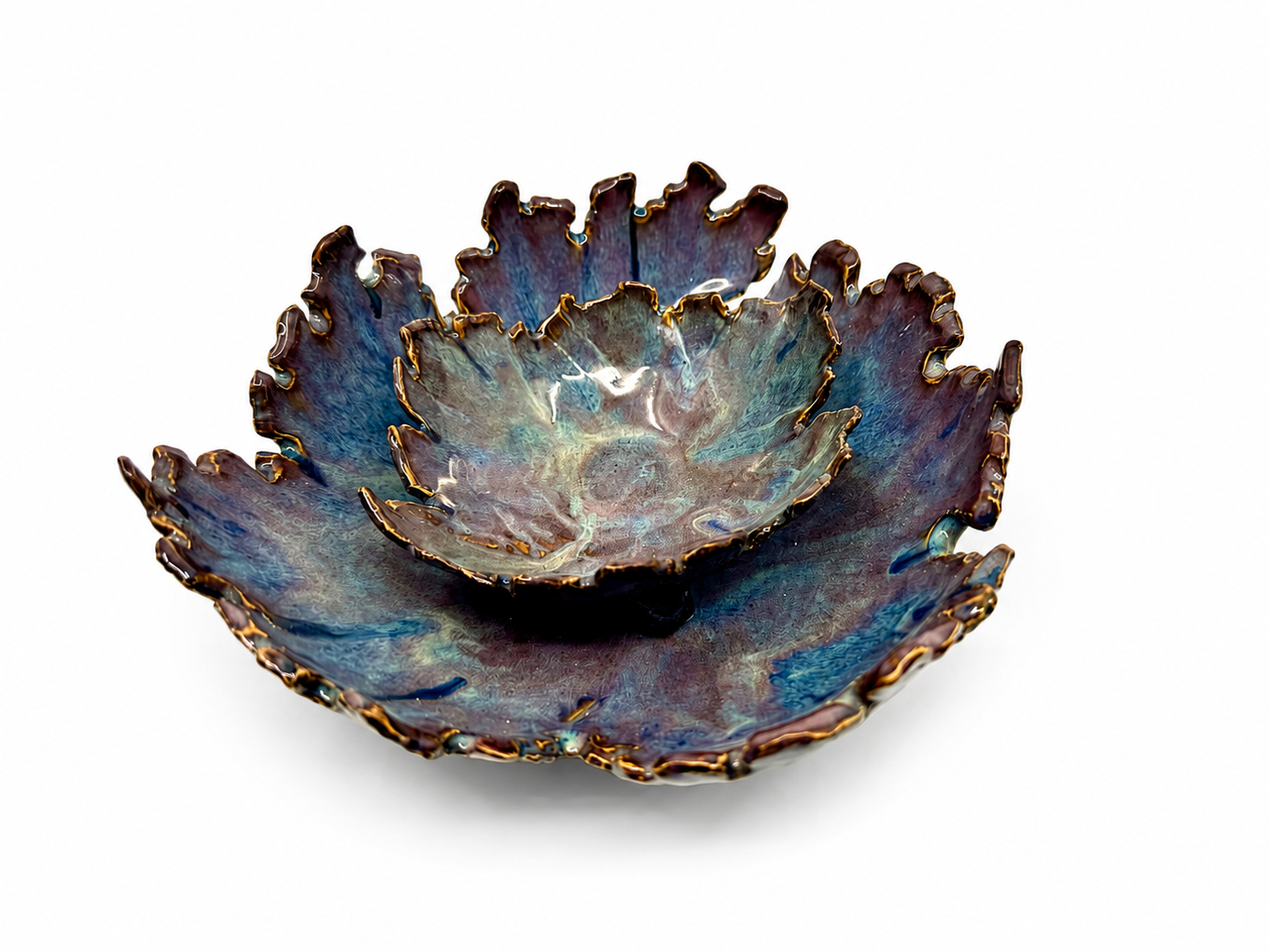 A decorative ceramic bowl resembling a blooming flower with ruffled, layered petals in shades of blue, purple, and brown with metallic gold accents on the edges, placed on a white background.