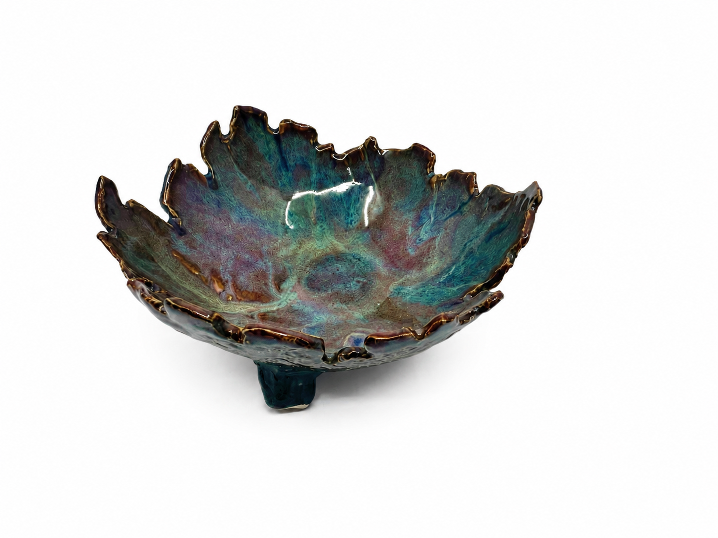 A decorative ceramic bowl with a ruffled edge and a multicolored, iridescent glaze on a white background.
