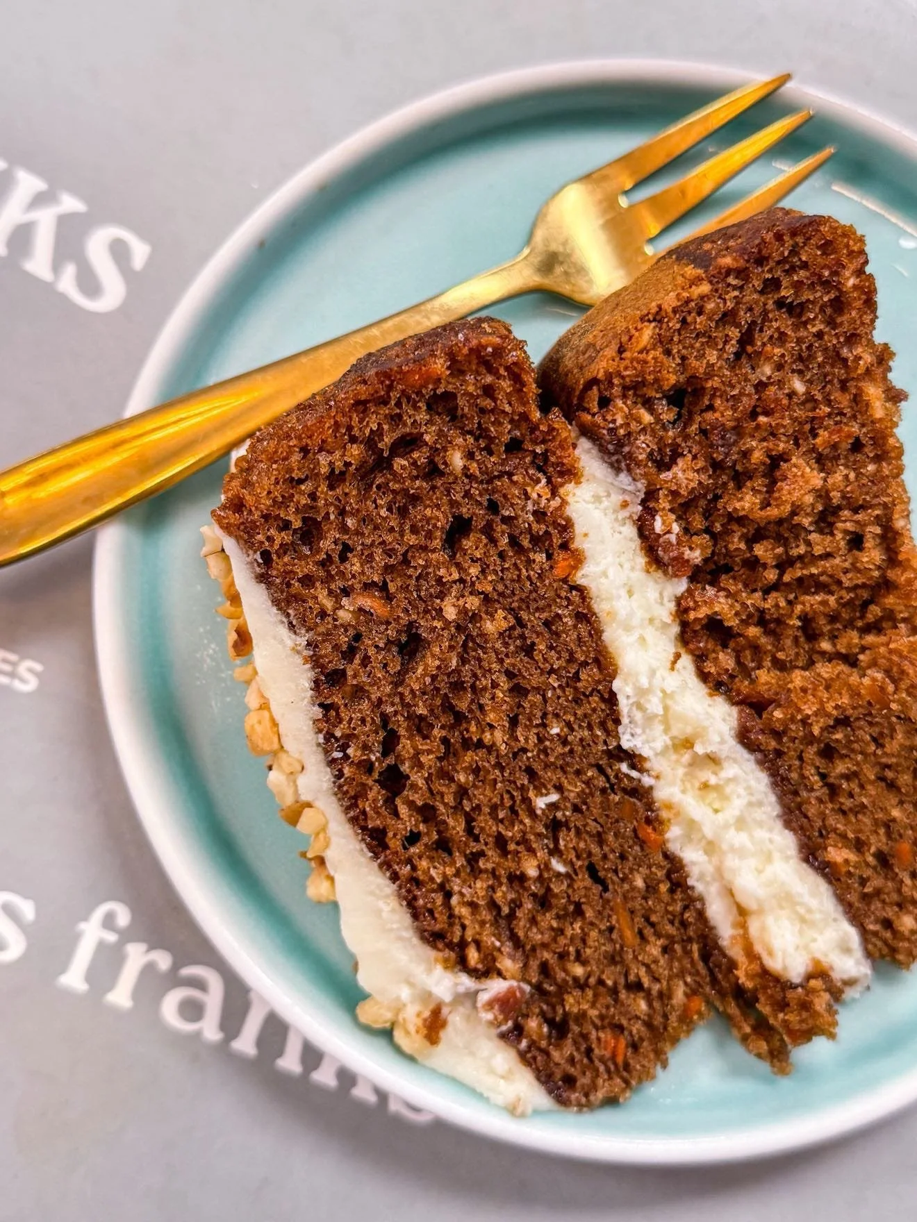 Slice of chocolate cake with white frosting on a blue plate, with a gold-colored fork on the side.