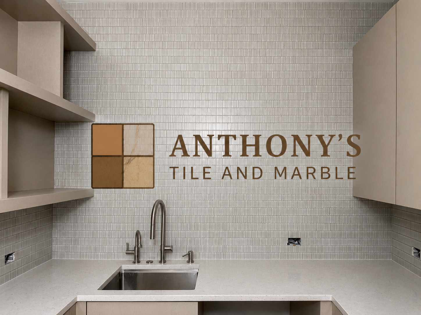 Interior view of a tile and marble showroom with a wall sign reading "Anthony's Tile and Marble," beige shelves, and a countertop with a stainless steel sink.