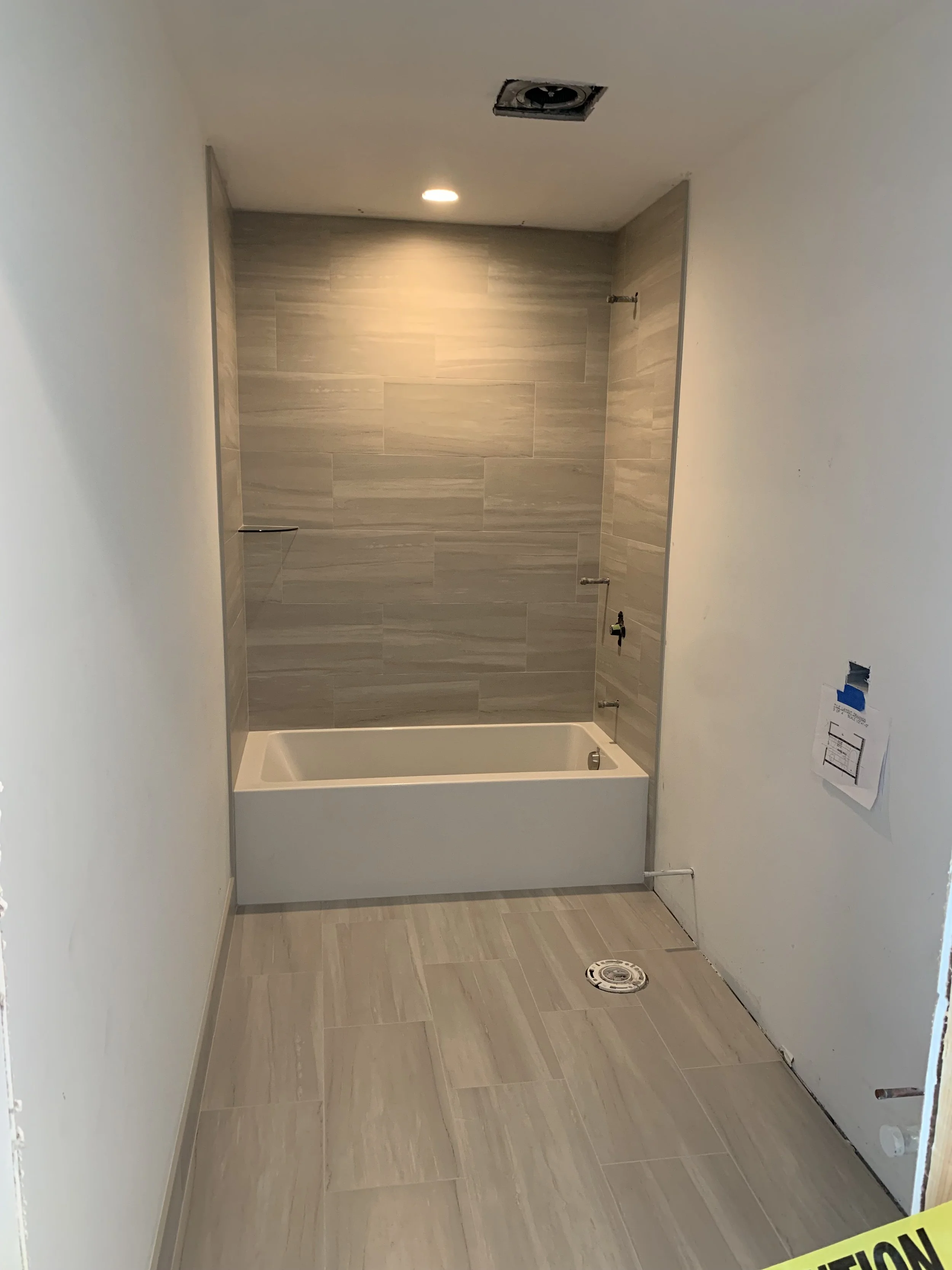 Bathroom under renovation with a bathtub, tiled wall, and ceiling light