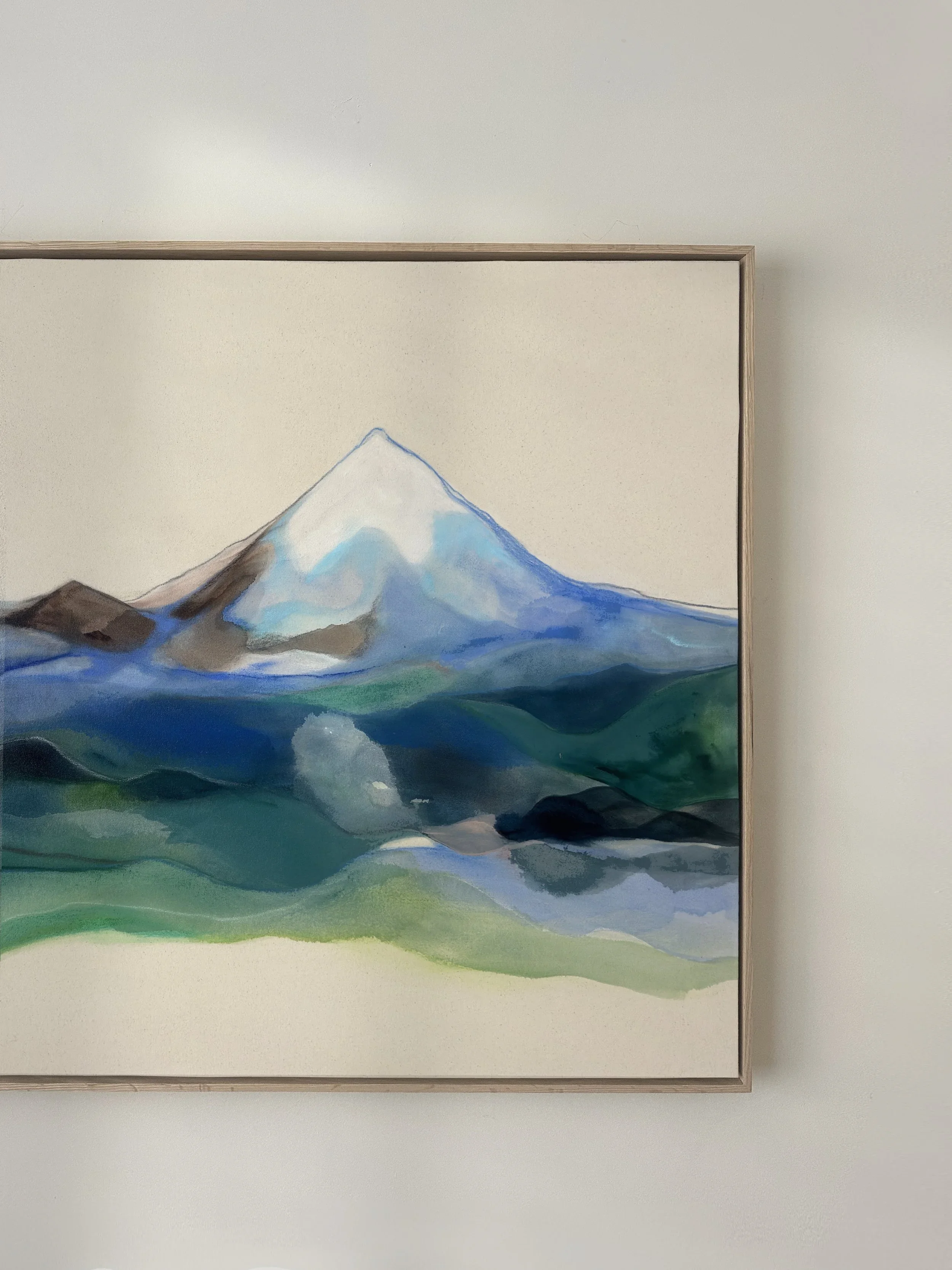 Watercolor painting of a mountain with snow-capped peak and green, blue, and brown landscape in the foreground.