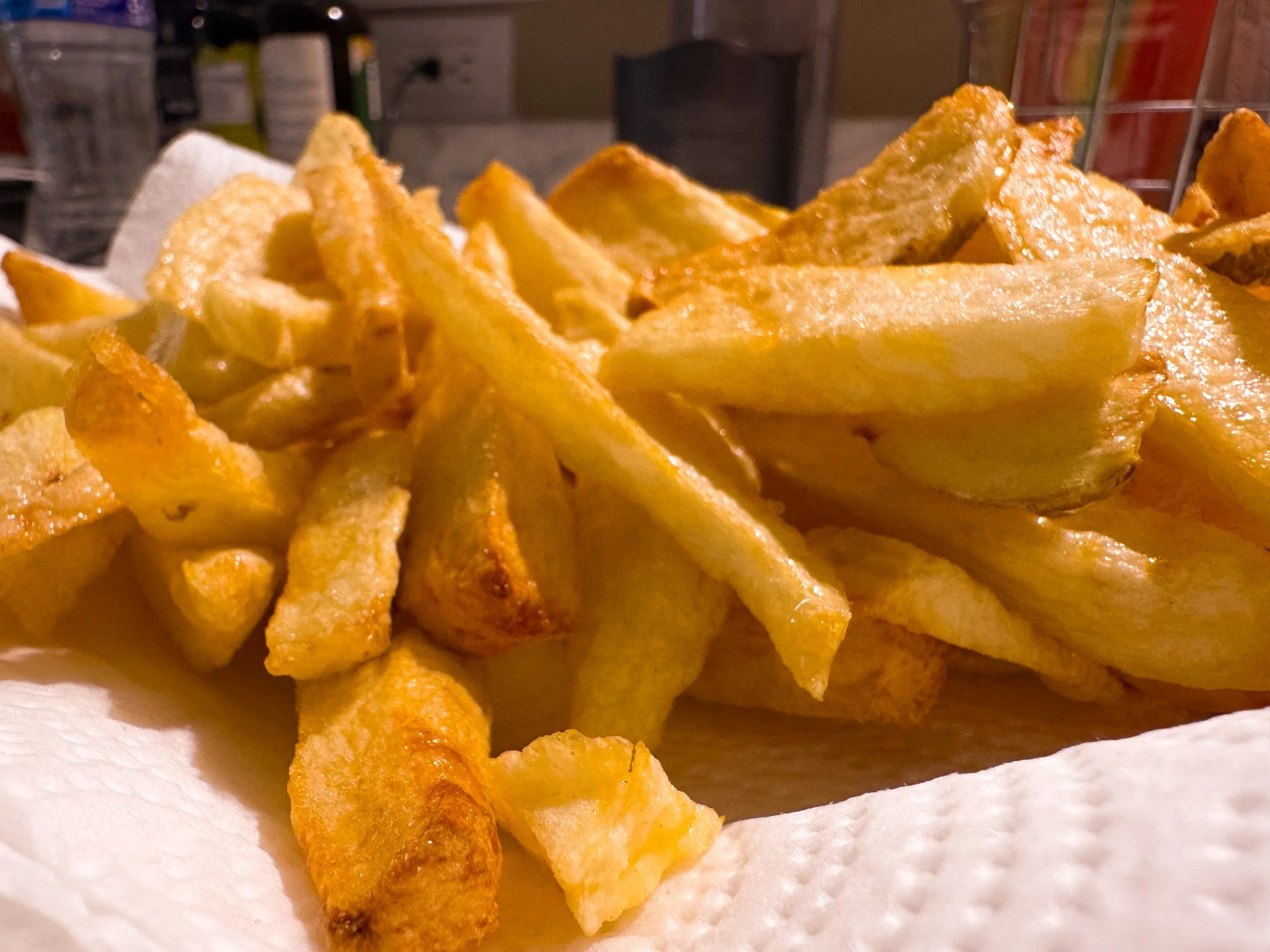 Close-up of a pile of French fries on a white paper towel.