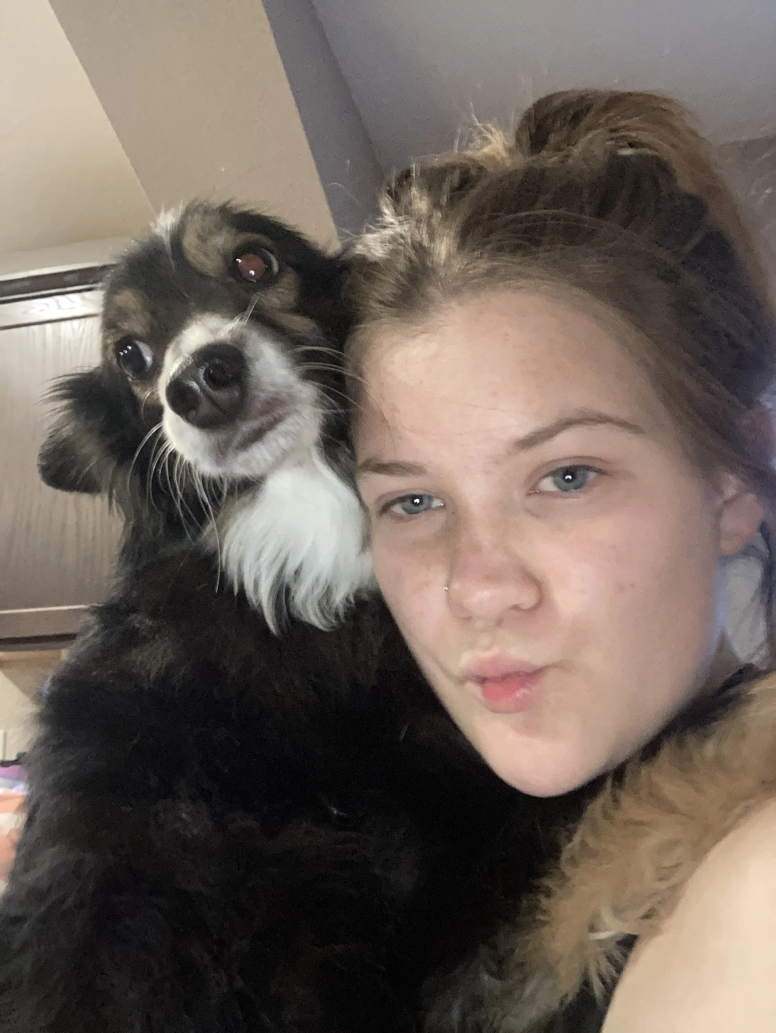 a girl posing for the camera while holding a black and white dog